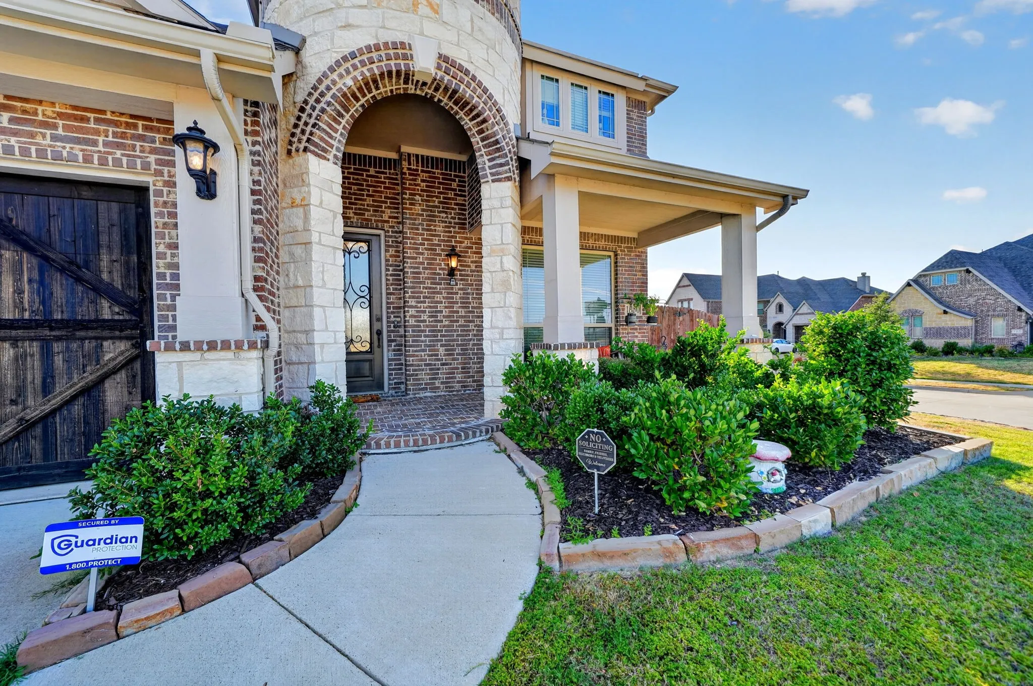 Brick and stone exterior featuring an arched entry, covered front porch, and decorative front door
