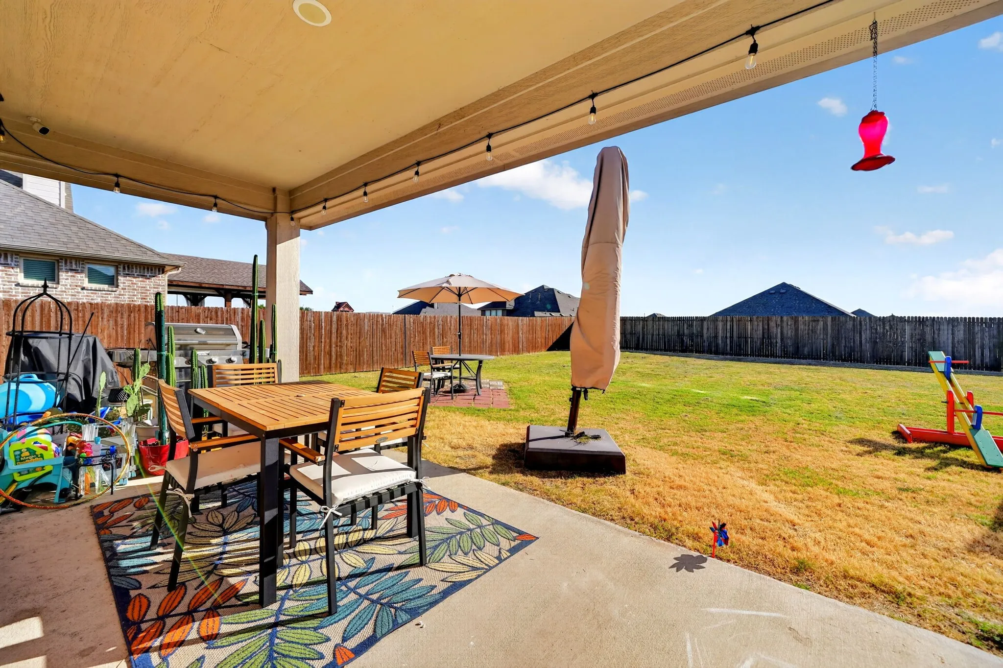Covered patio with integrated string lighting and an expansive lawn area