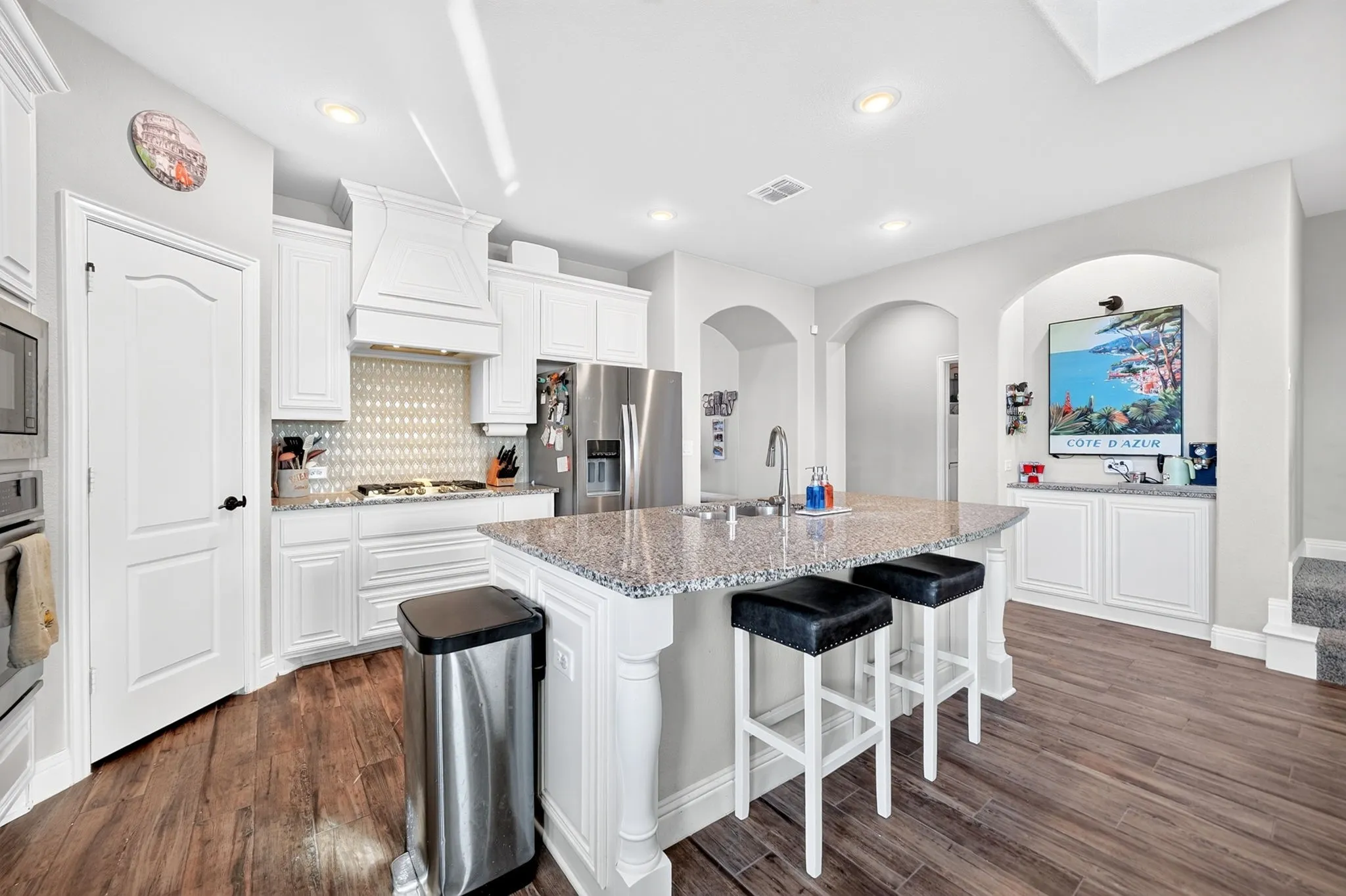 Kitchen featuring wood-finish flooring, white cabinetry, a kitchen island with a granite countertop, stainless steel appliances, and recessed lighting