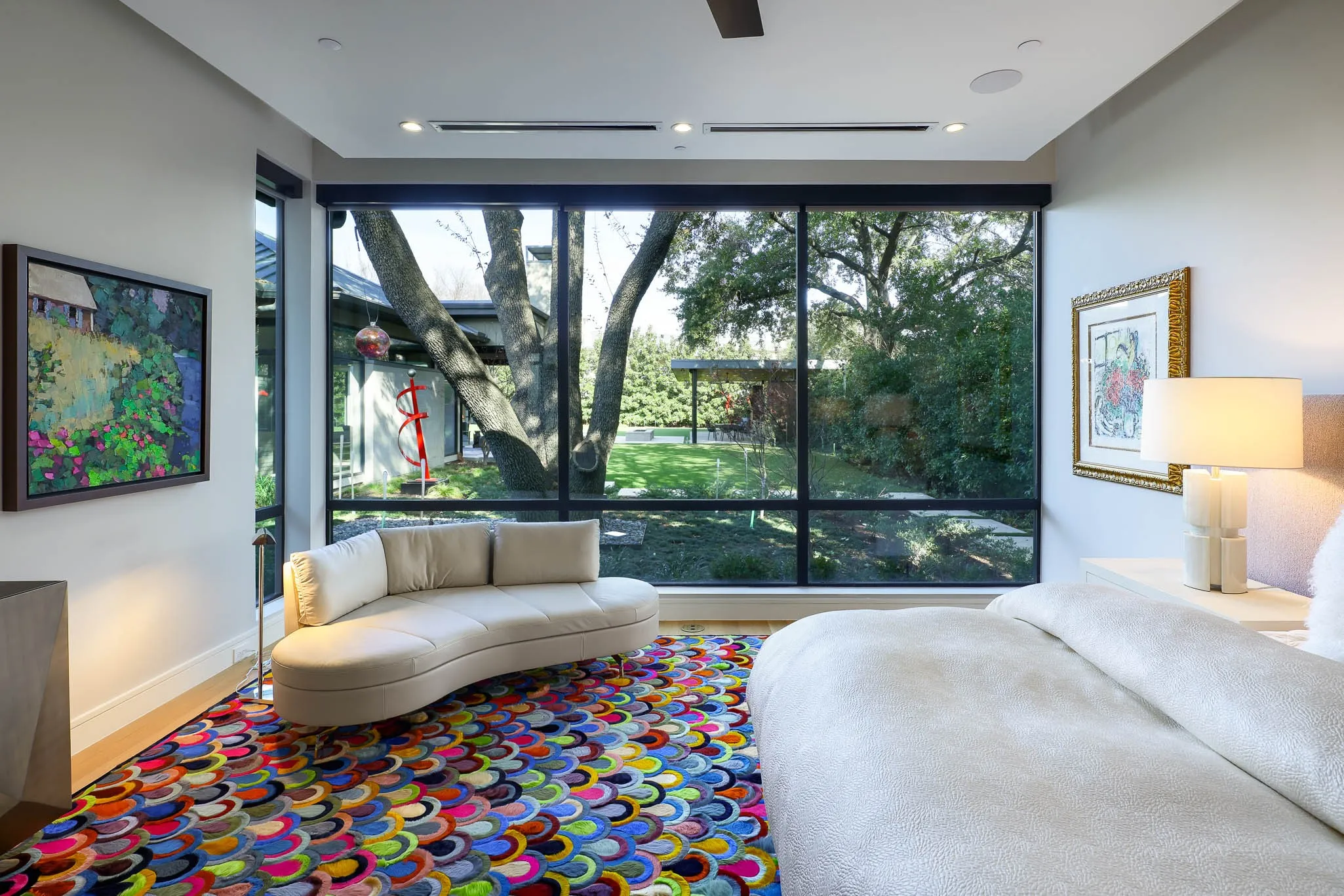 Primary bedroom with sitting area overlooking landscaped backyard