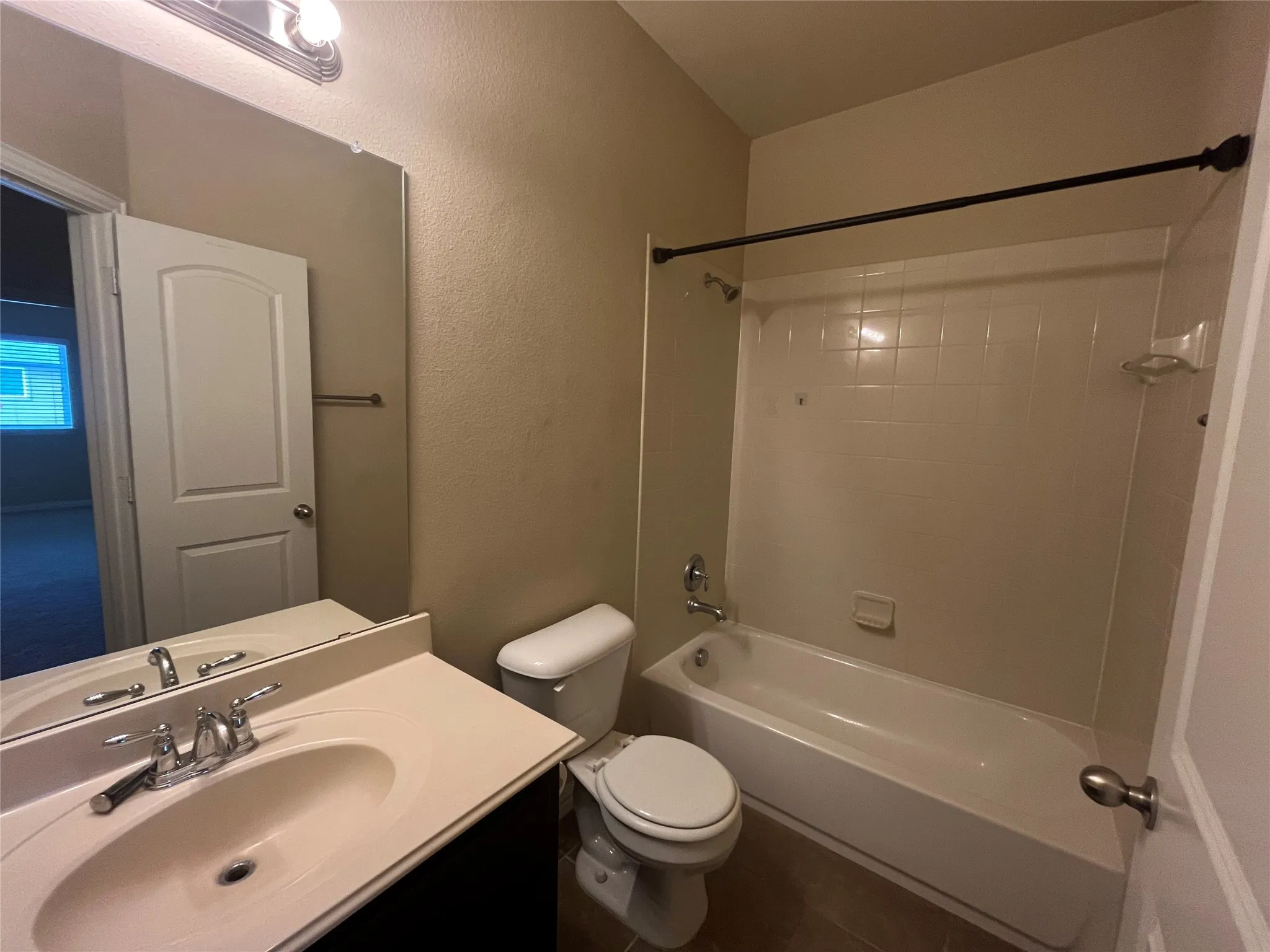 Bathroom featuring a single vanity with integrated sink, chrome fixtures, tile flooring, and a tub with shower