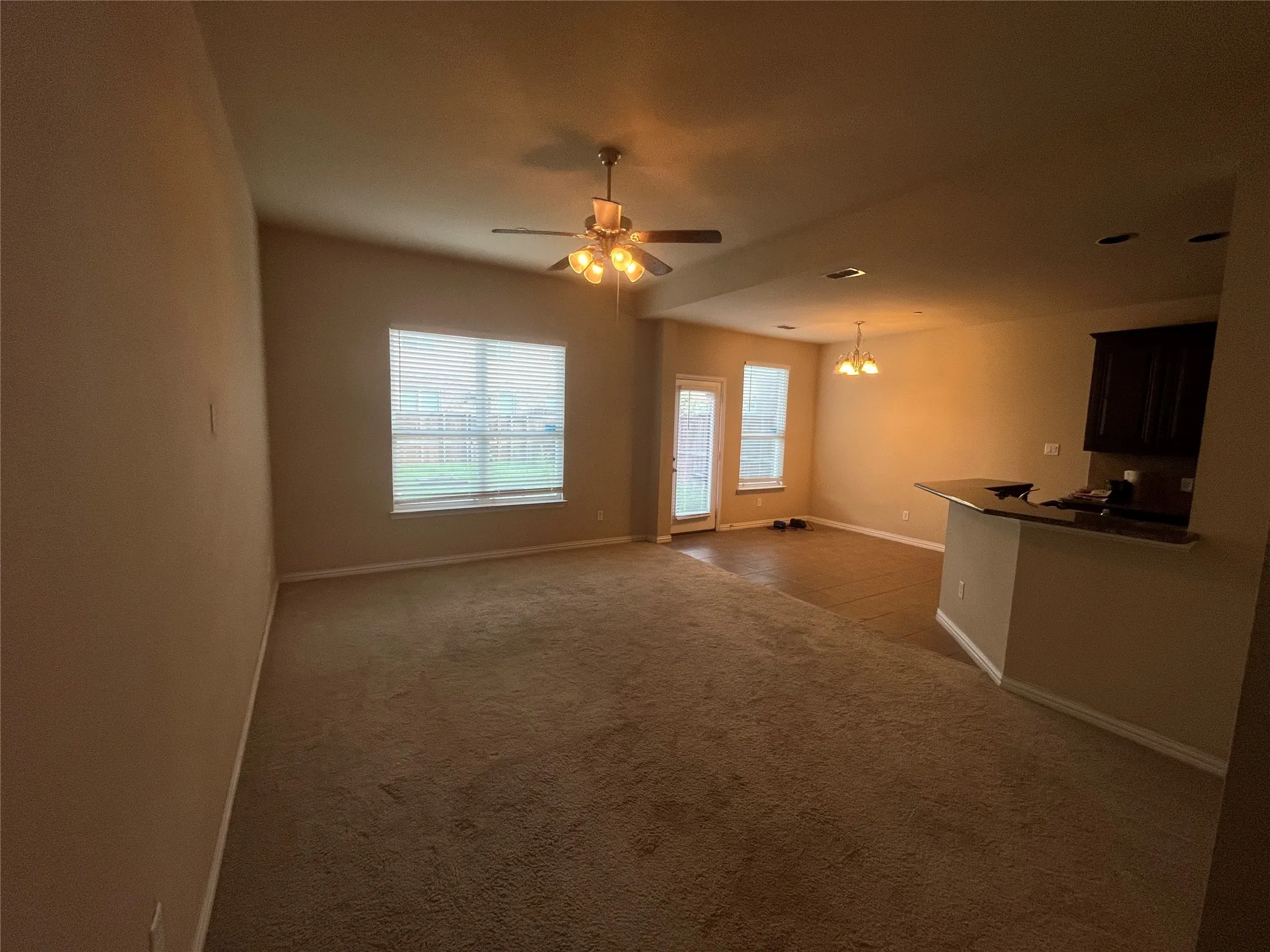 Vaulted ceiling, ceiling fan with integrated lighting, window with blinds, French door with integrated blinds, and a built-in counter-height bar with a dark countertop