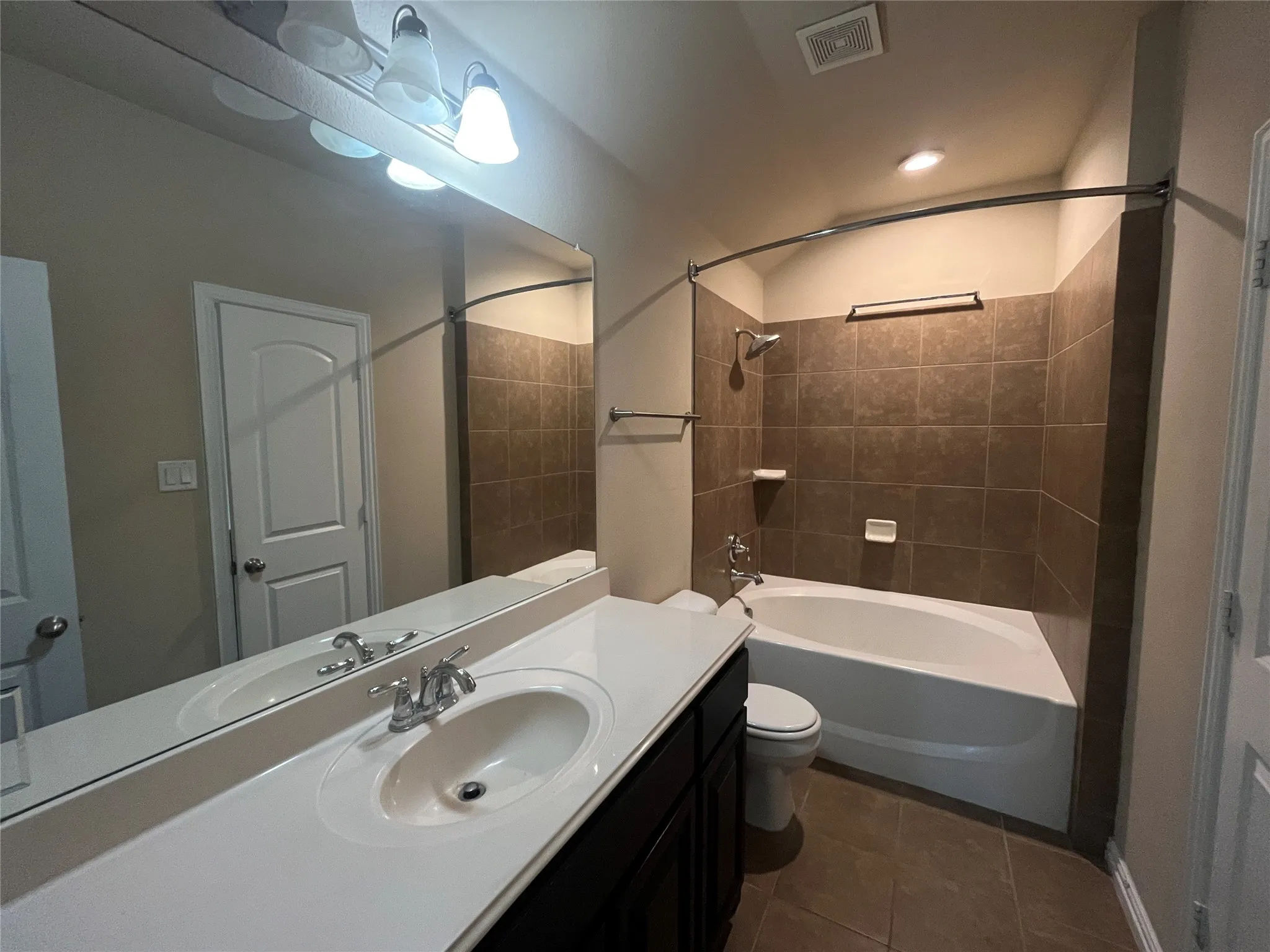 Spacious vanity with dual sinks, expansive mirror, and overhead lighting