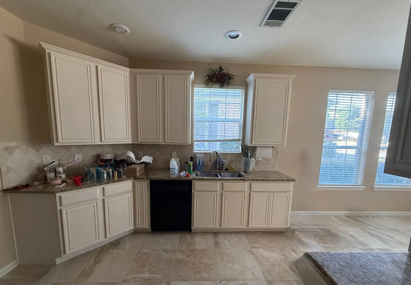 L-shaped kitchen featuring cream cabinetry, granite-finish countertops, and a tile backsplash