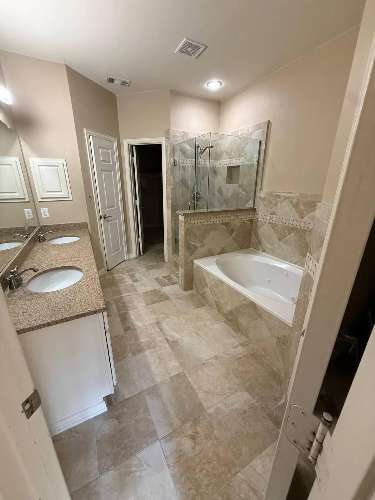 Dual vanity with undermount sinks, stone-finish countertops, and white cabinetry