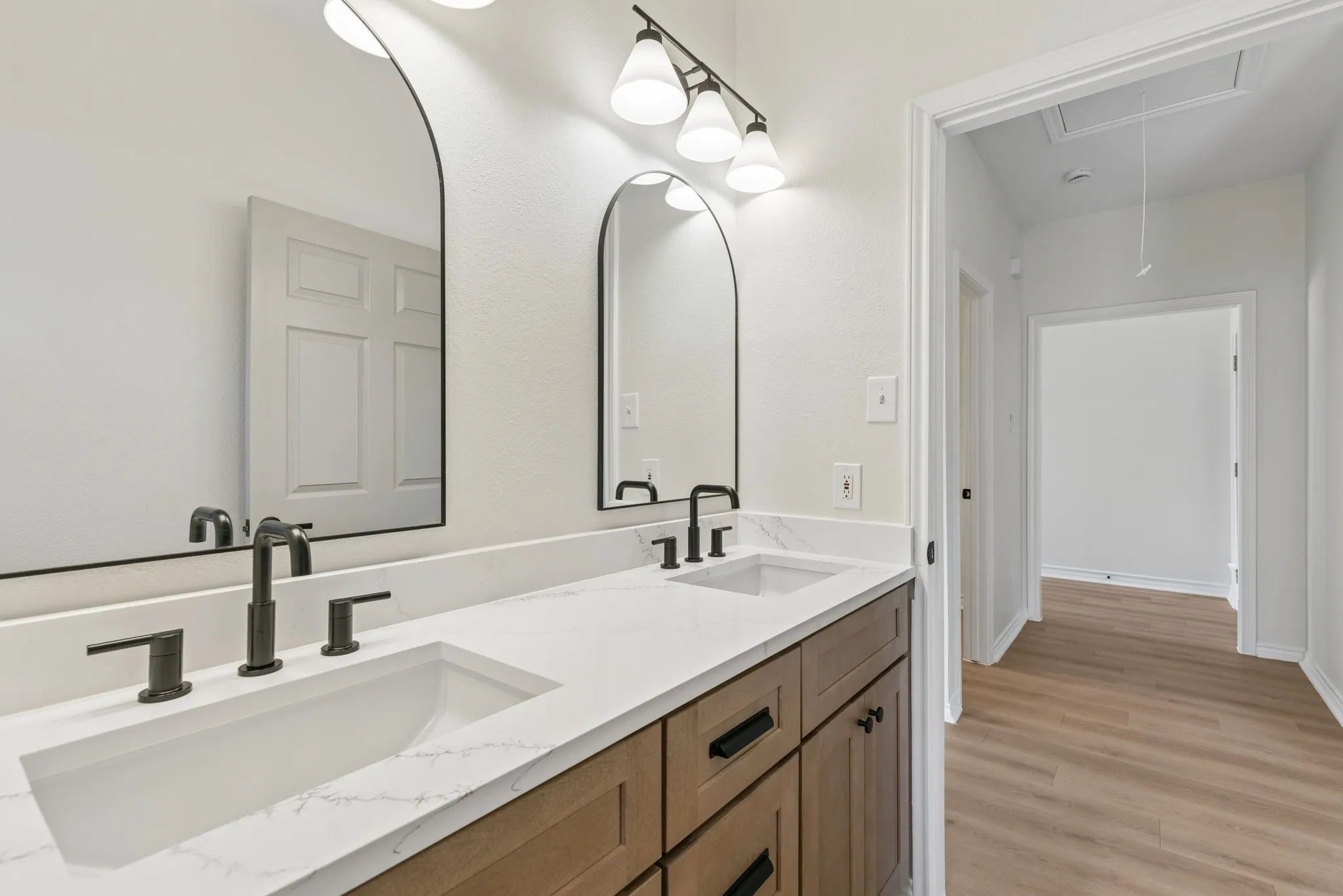 Dual vanity with undermount sinks, stone-finish countertop, dark wood-finish cabinetry, and black fixtures