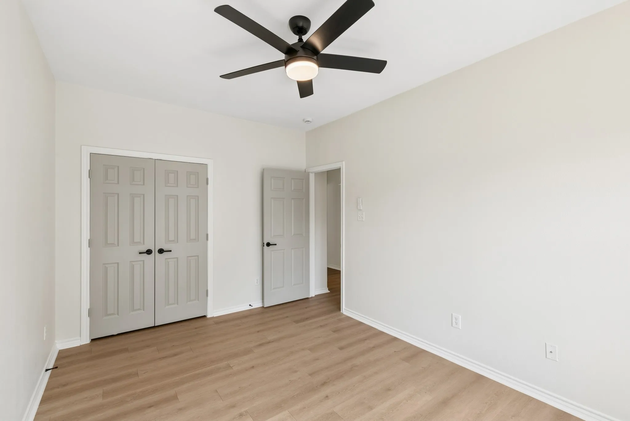 Recessed lighting, wood-finish flooring, ceiling fan with integrated light, light-colored walls, and panel doors