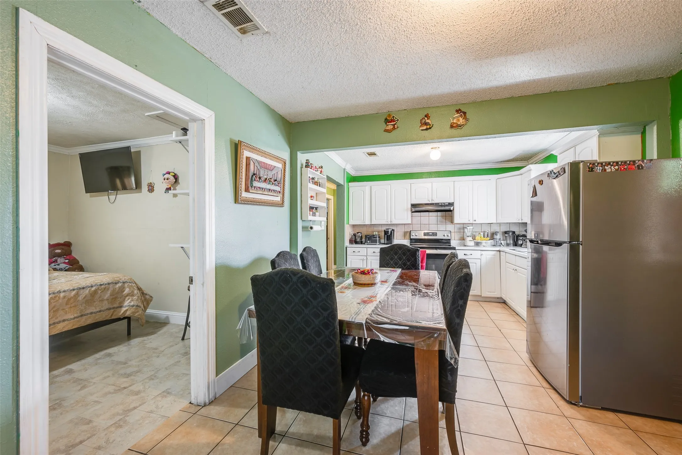 Kitchen featuring white cabinetry, stainless steel refrigerator, and tiled flooring
