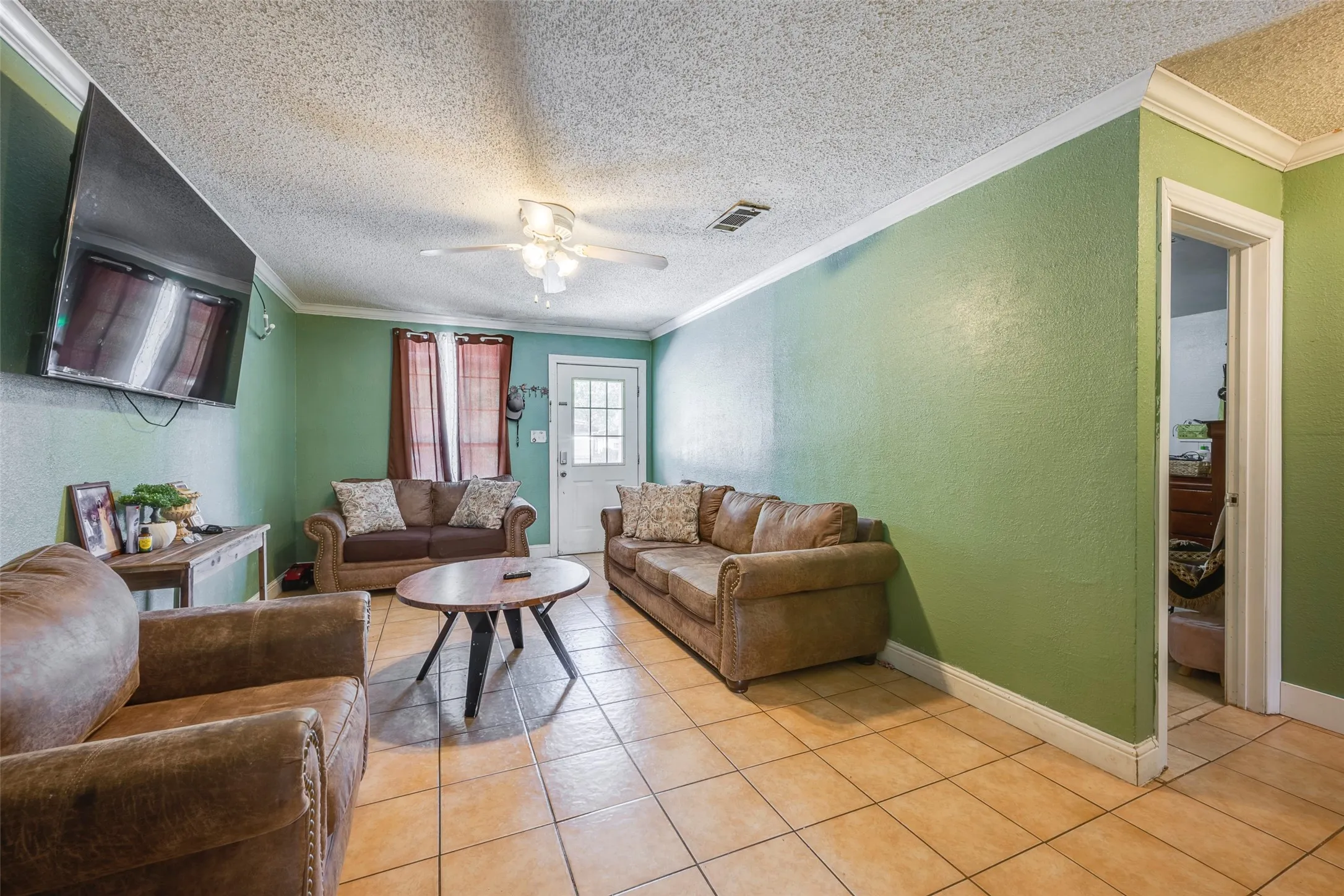 Tile flooring, neutral wall tones, ceiling fan, crown molding, and white trim