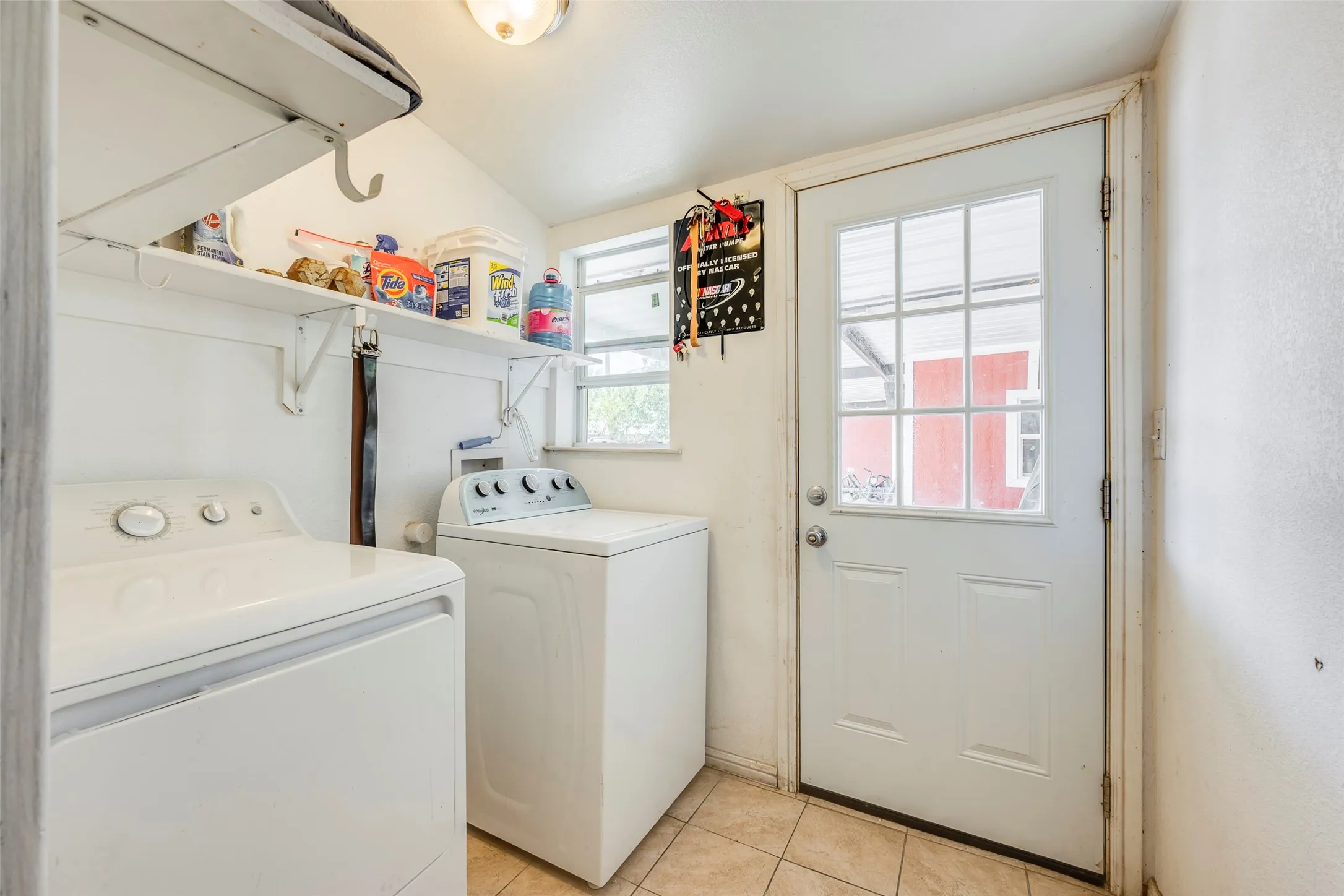 Laundry area with tile flooring, wall-mounted shelving, and a glass-paneled exterior door
