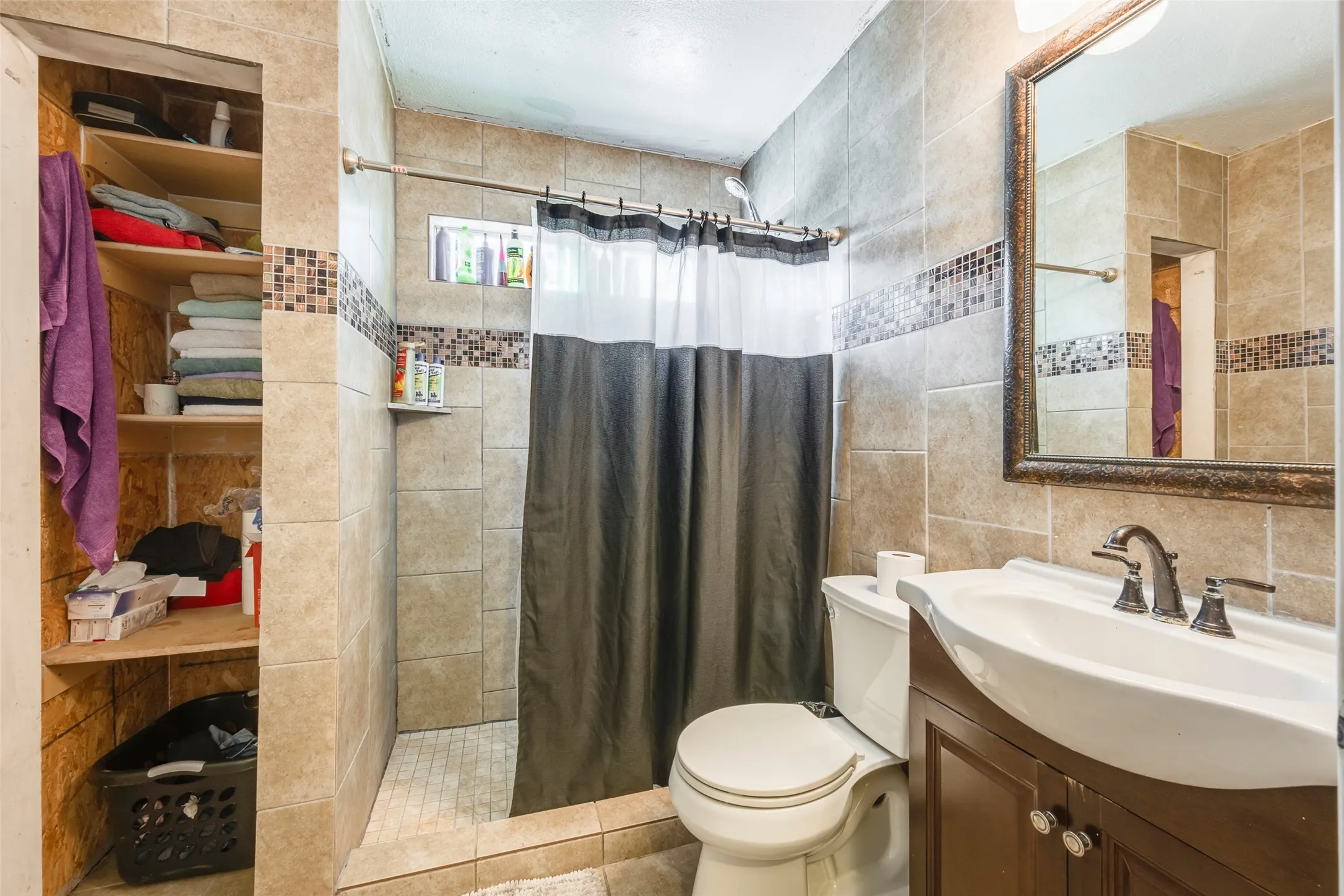 Tile-surround shower with a mosaic accent band and a recessed niche
