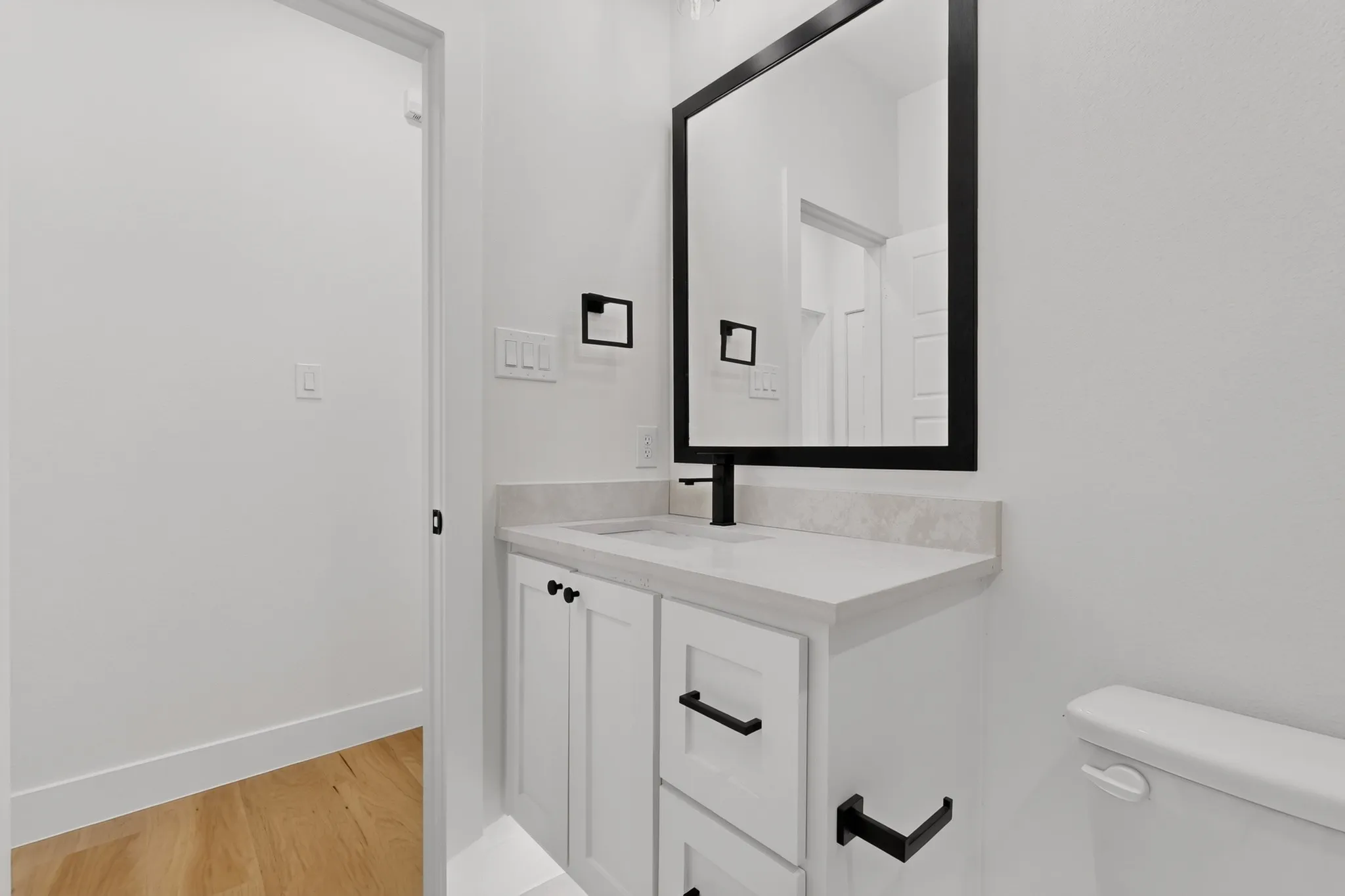 White vanity with shaker-style cabinetry, a built-in sink, and a light-colored countertop