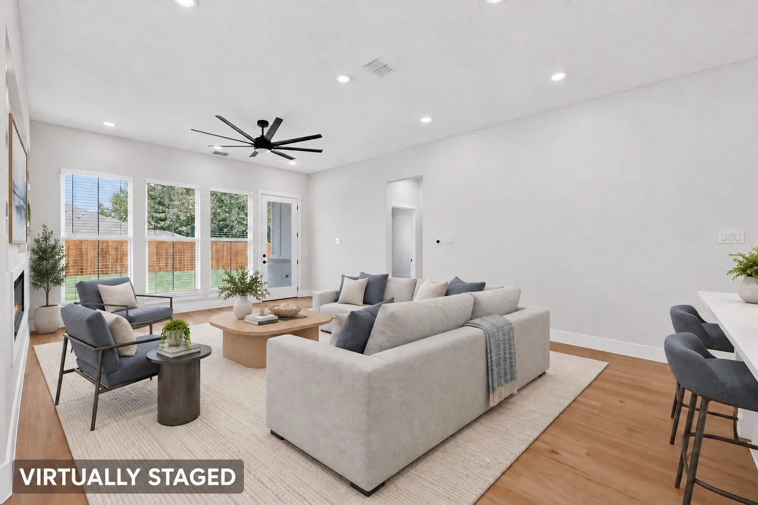 Spacious room featuring wood-finish flooring, a contemporary ceiling fan, recessed lighting, and multiple windows with blinds