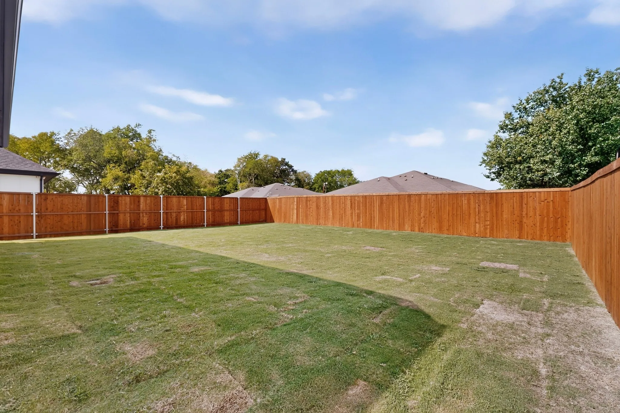 Expansive backyard featuring a manicured lawn and tall wood privacy fencing