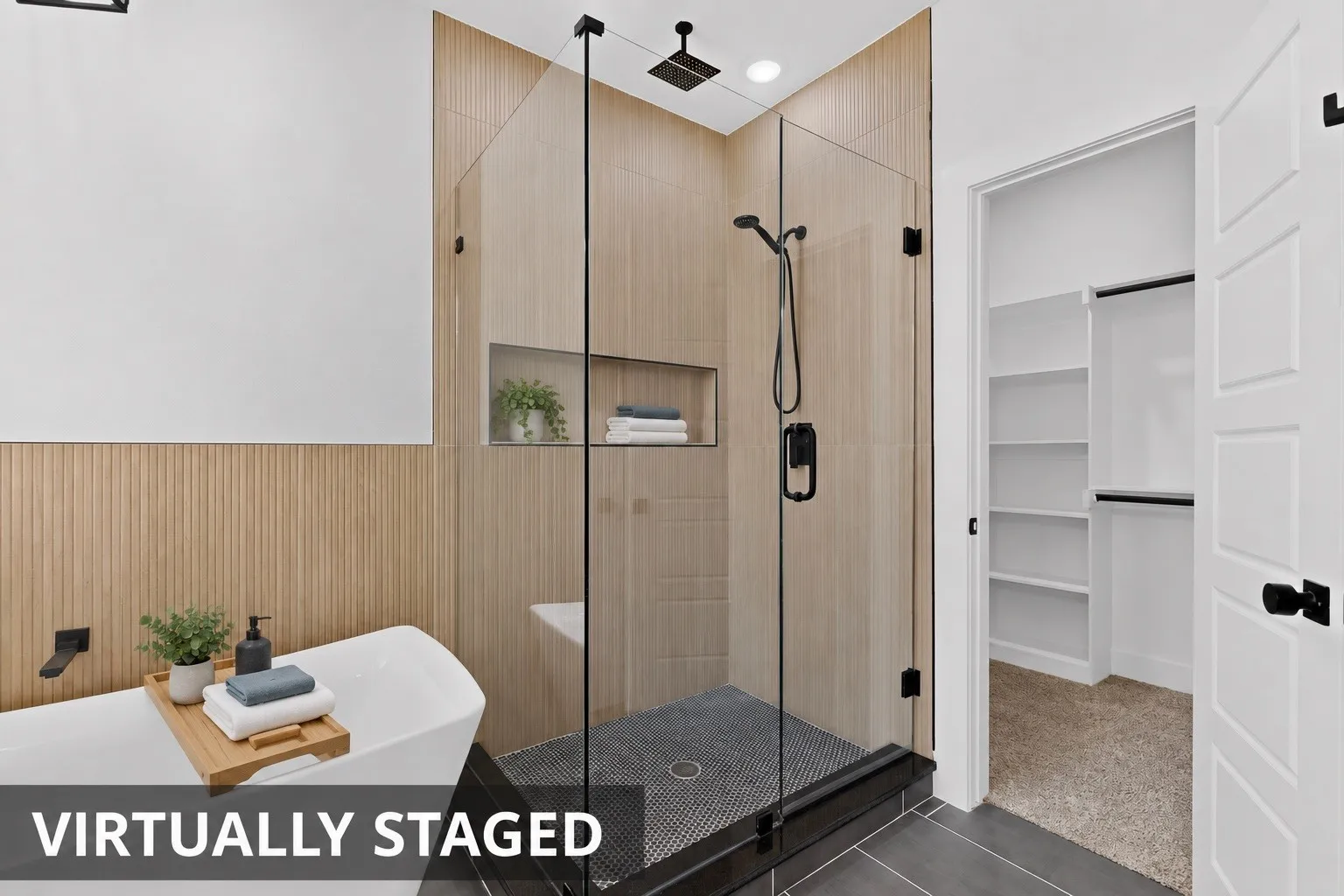 Walk-in shower with clear glass enclosure and black fixtures, featuring a built-in shower niche and tile flooring