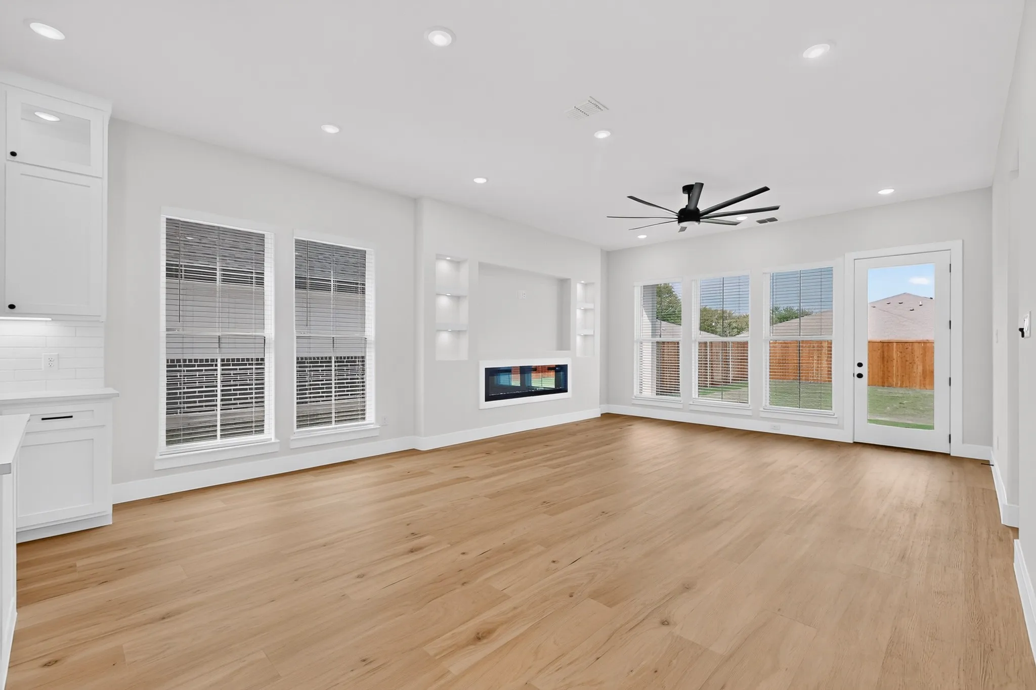 Recessed lighting, wood-finish flooring, built-in display niches, an electric fireplace, and a ceiling fan