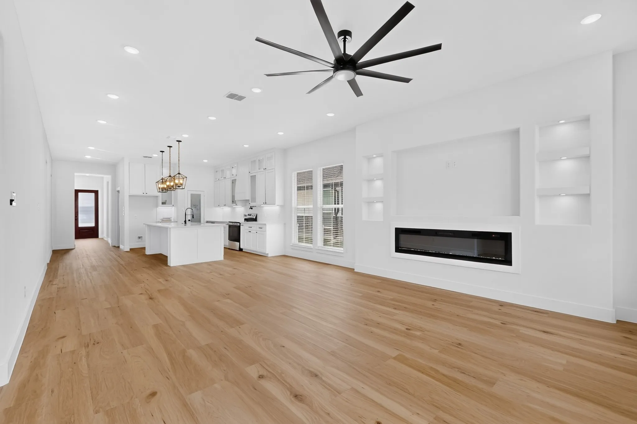 Light wood-finish flooring throughout, recessed lighting, and a modern ceiling fan