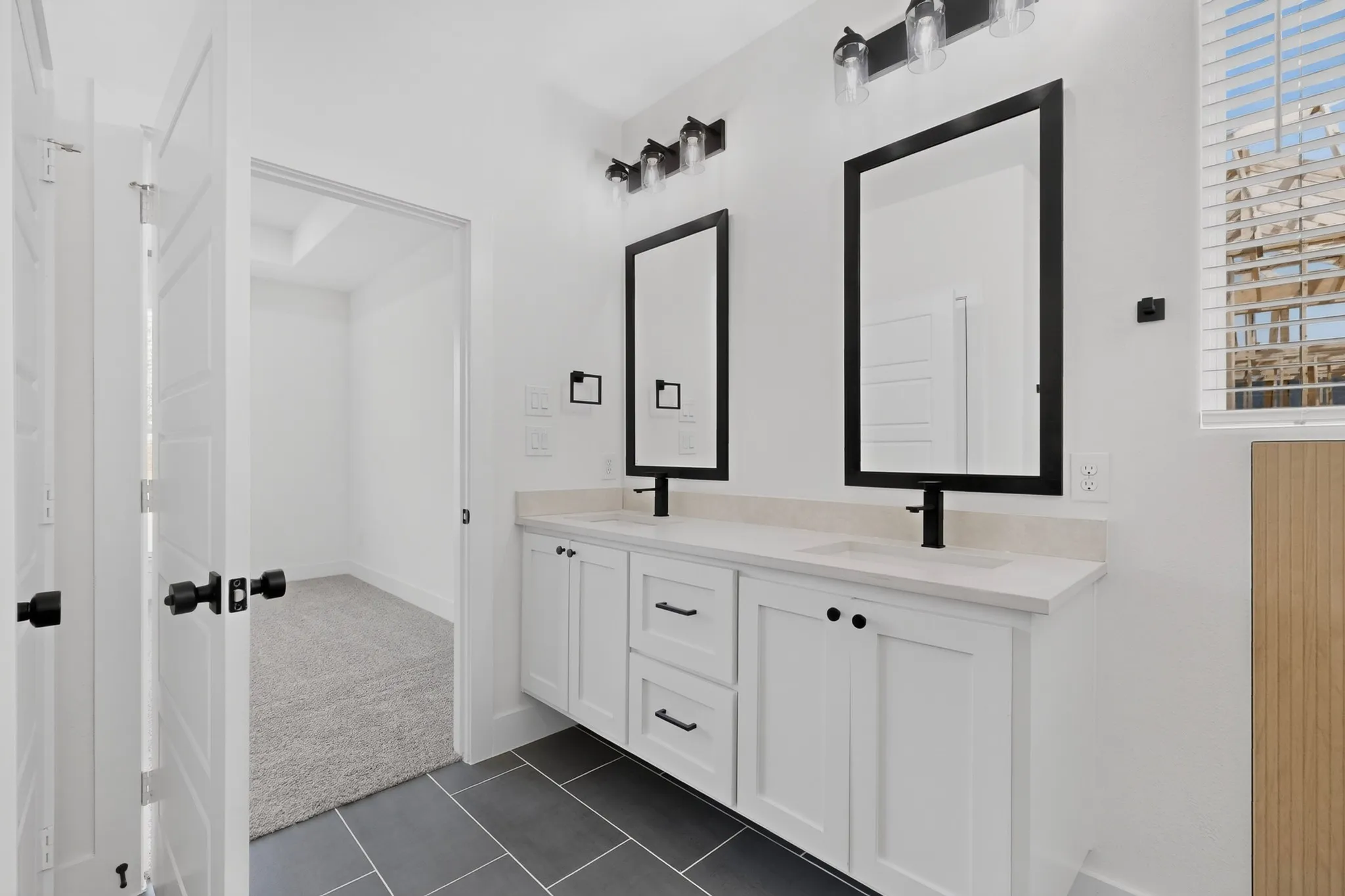 Dual vanity with white cabinetry, matte black hardware, and individual mirrors