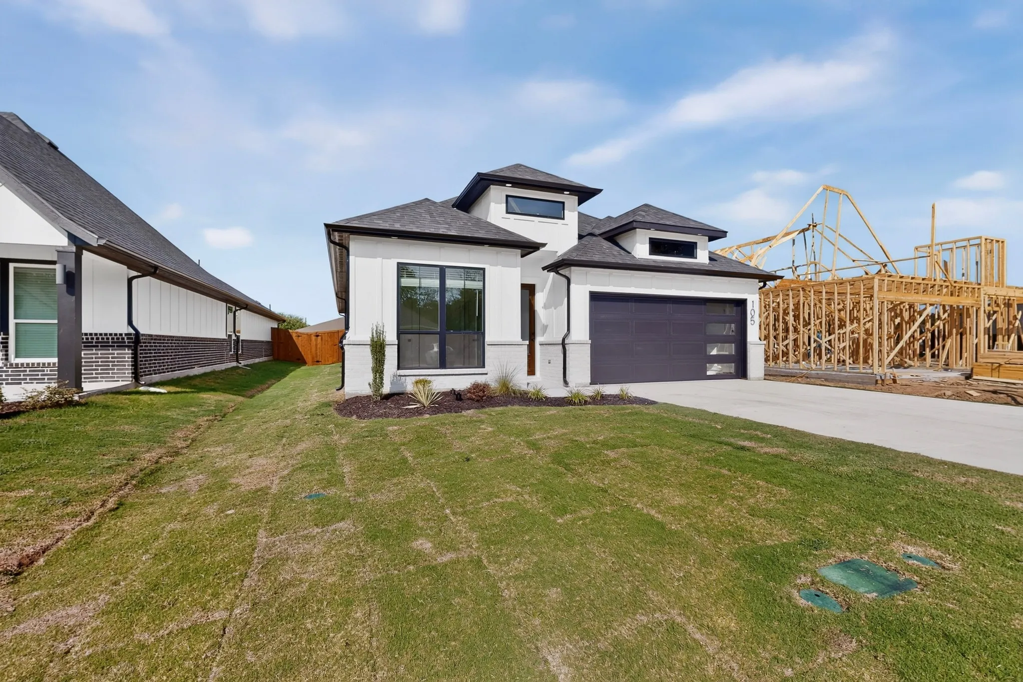 Modern exterior with a light stucco finish, dark trim, a two-car garage, and a concrete driveway