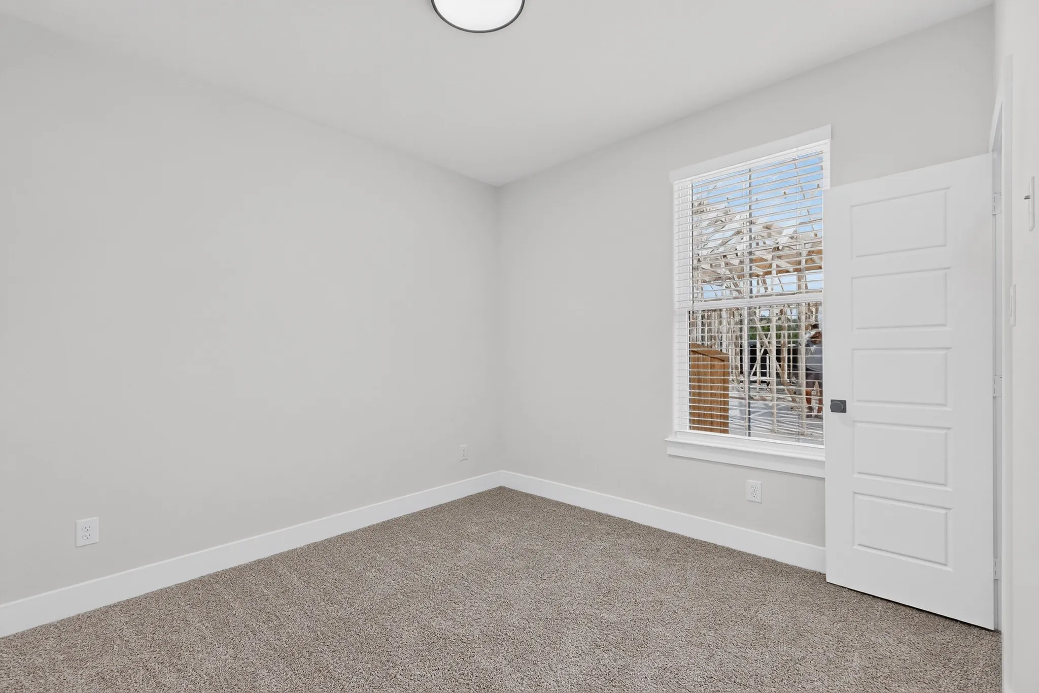 Neutral-toned carpeting, light gray wall paint, and a window with blinds