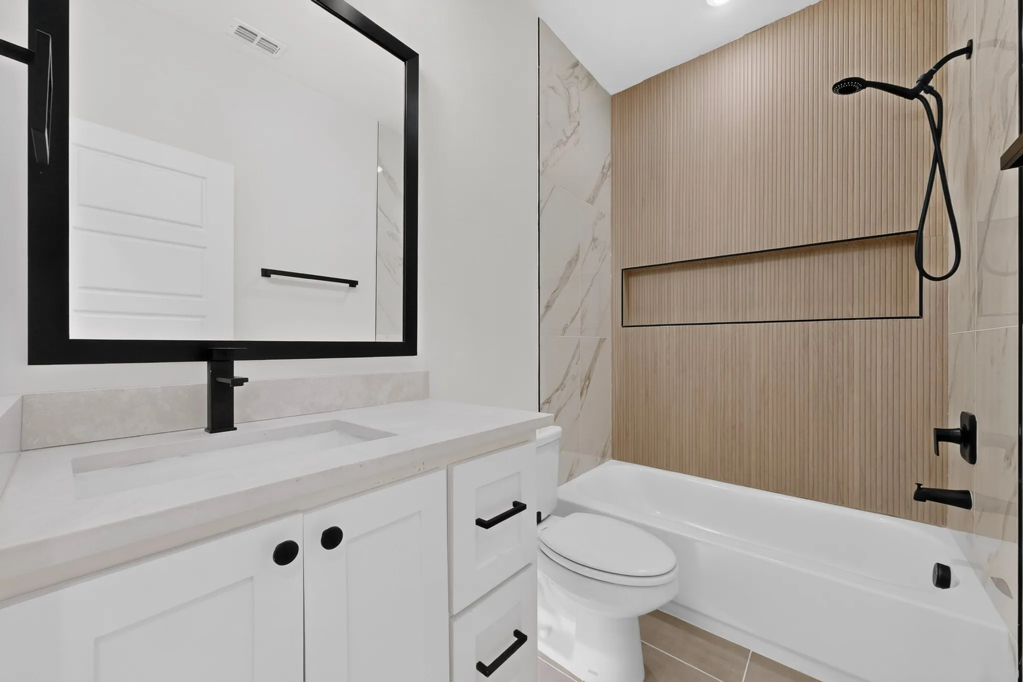 White vanity with matte black hardware, integrated sink, and black-framed mirror