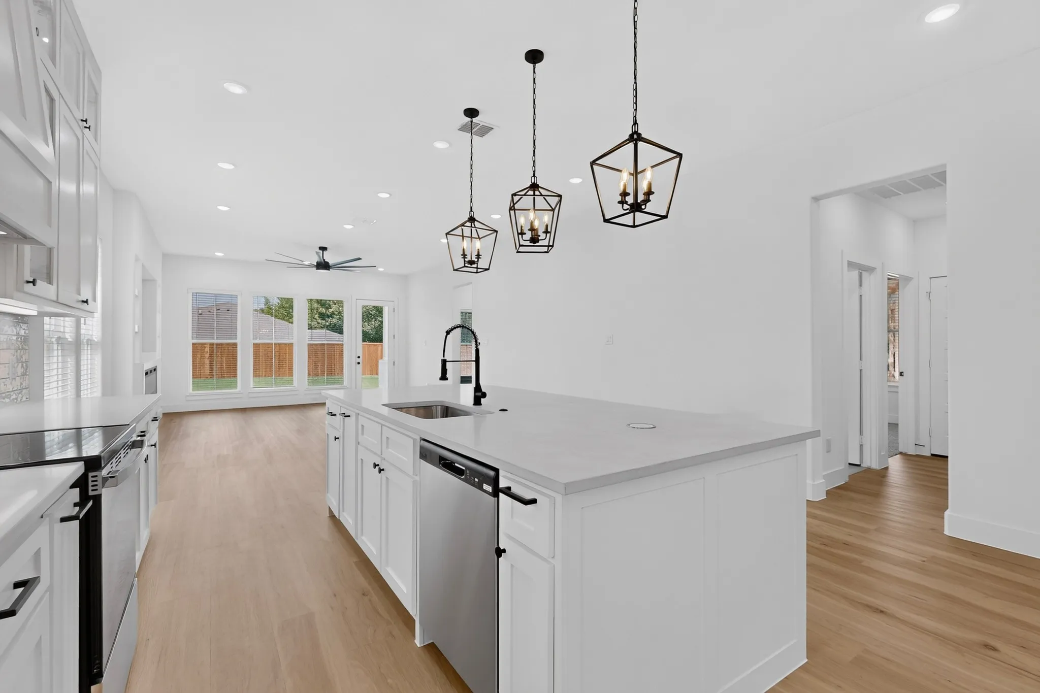 Expansive kitchen island with an undermount sink, stainless steel appliances, and pendant lighting