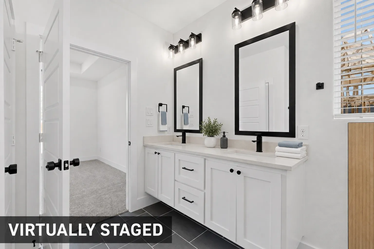Dual vanities with white cabinetry, black hardware, and stone countertops