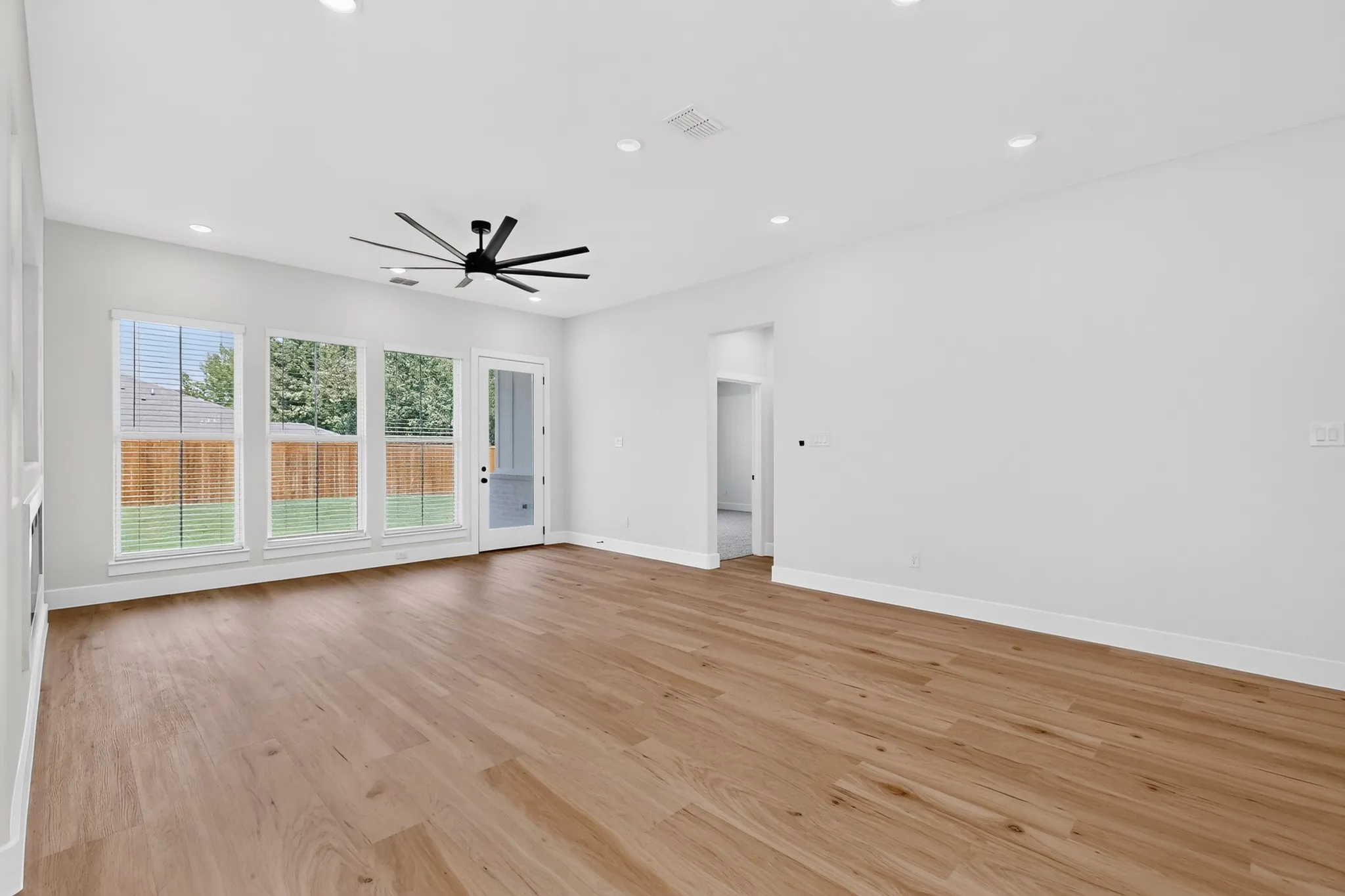 Spacious room featuring wood-finish flooring, recessed lighting, and a contemporary ceiling fan