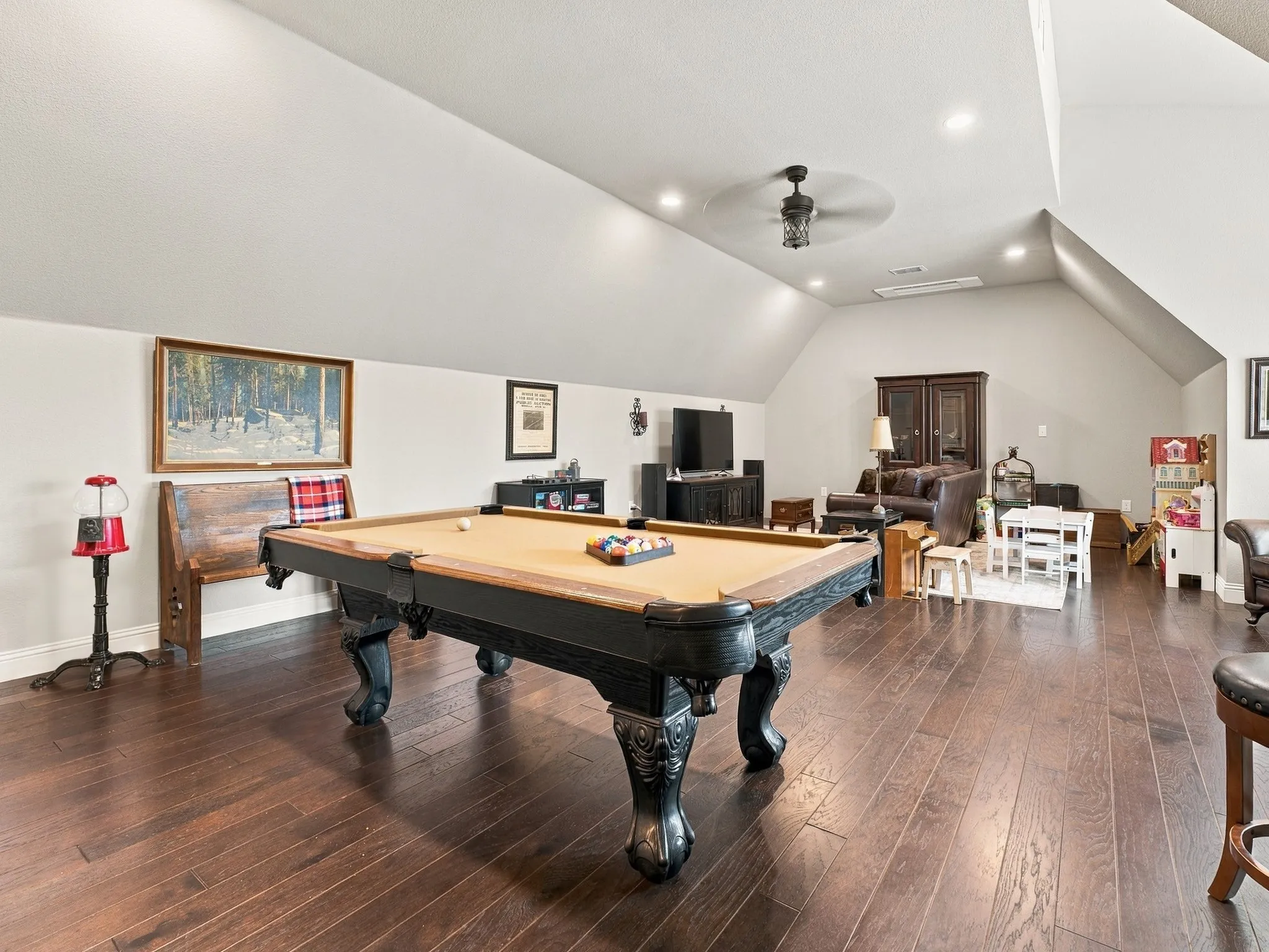 Sloped ceilings, rich wood-finish flooring, recessed lighting, and a ceiling fan