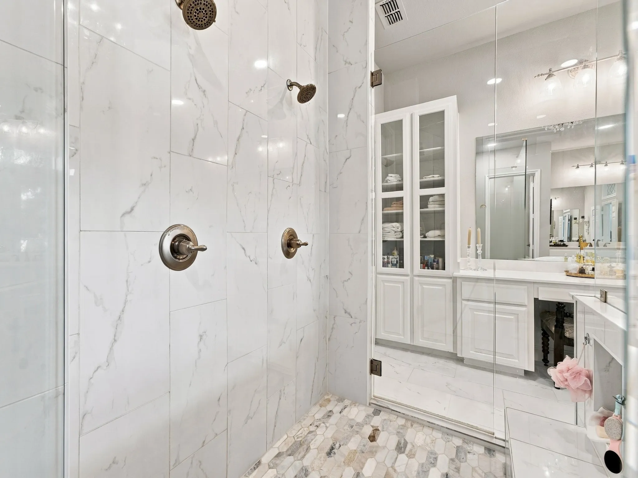 Spa-inspired primary bathroom featuring a walk-in shower with marble-look tile surround, dual showerheads, and frameless glass enclosure