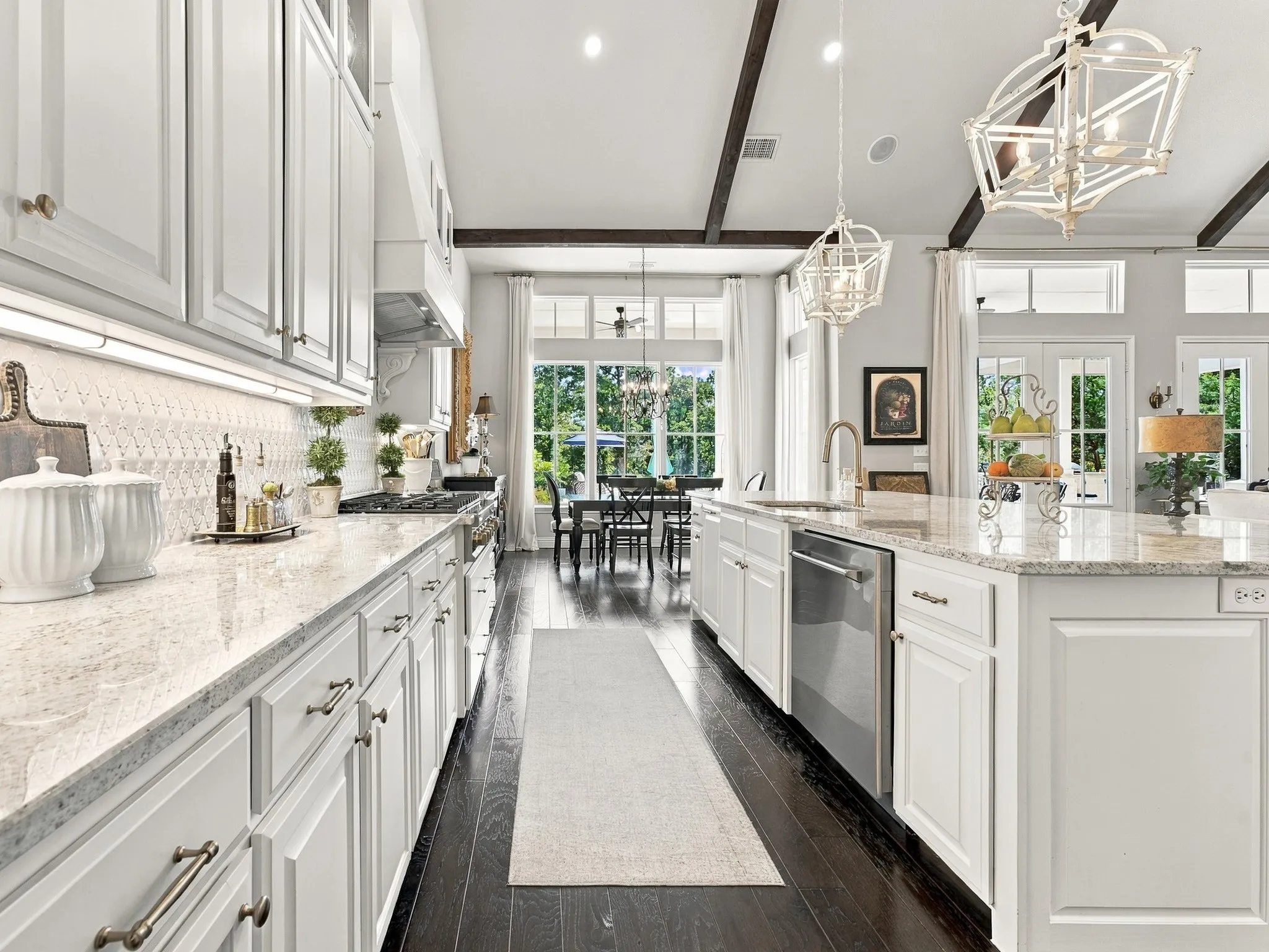 Kitchen featuring white cabinetry, light-colored countertops, dark wood-finish flooring, a kitchen island with sink, and exposed ceiling beams