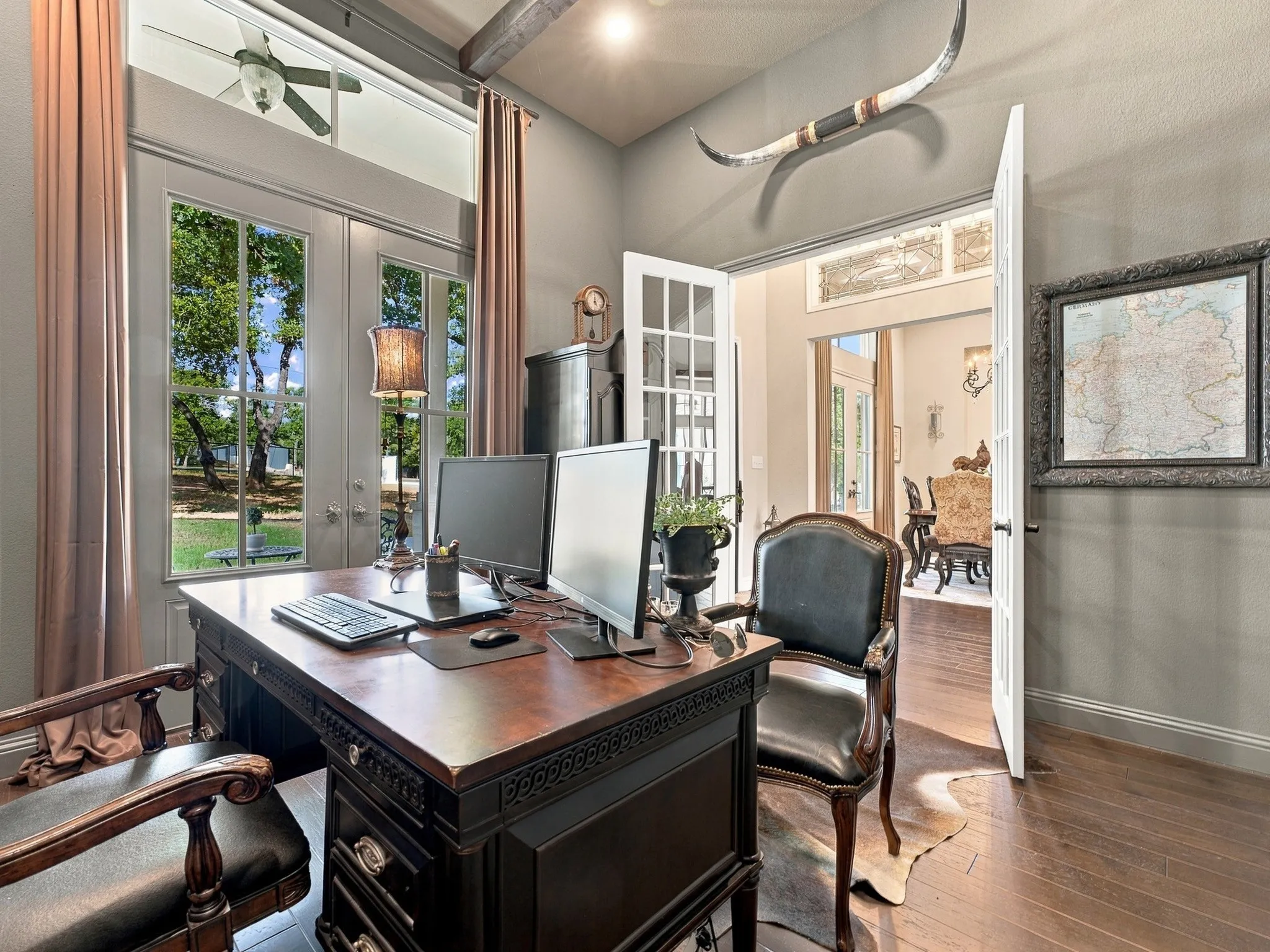 Hardwood flooring, exposed ceiling beams, built-in ceiling fan, transom window, and French doors