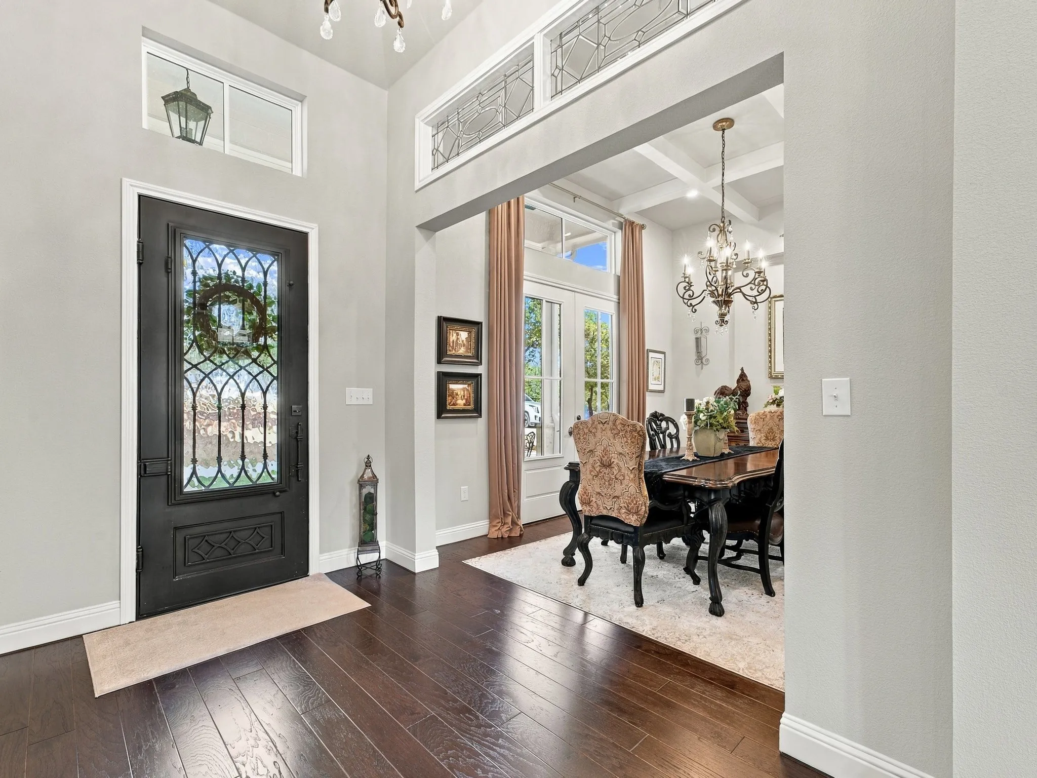 Hardwood-finish flooring, a decorative glass entry door, and transoms with decorative glass above