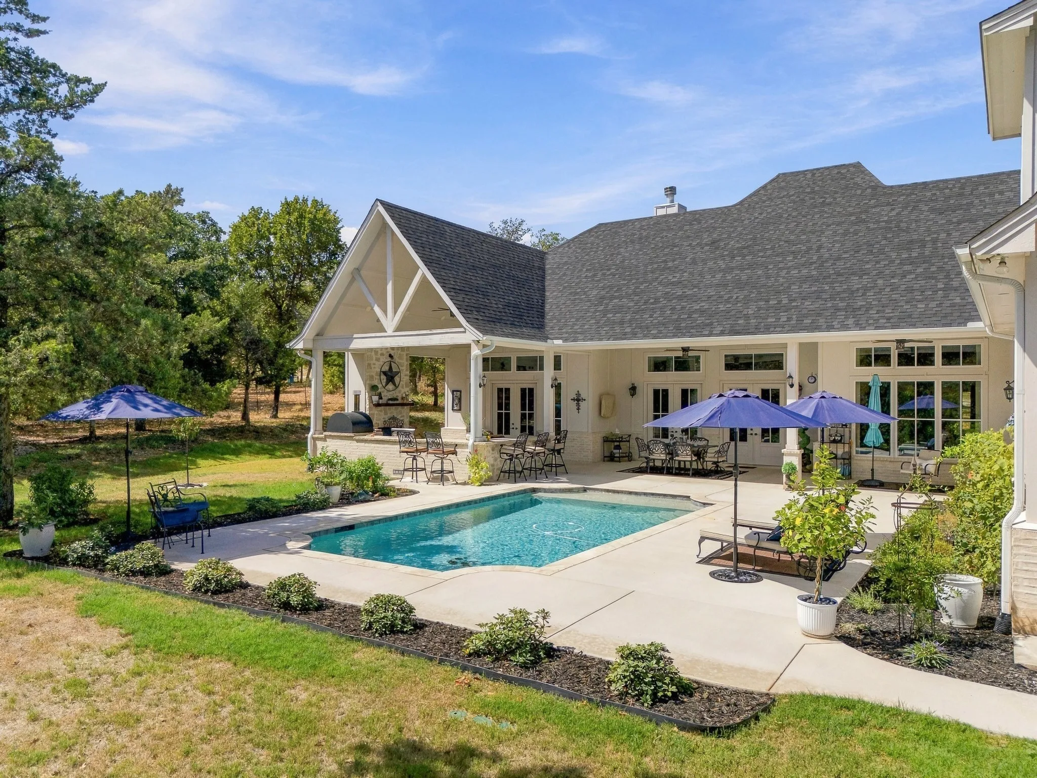 Expansive patio with an in-ground swimming pool, covered outdoor living area, and built-in outdoor kitchen