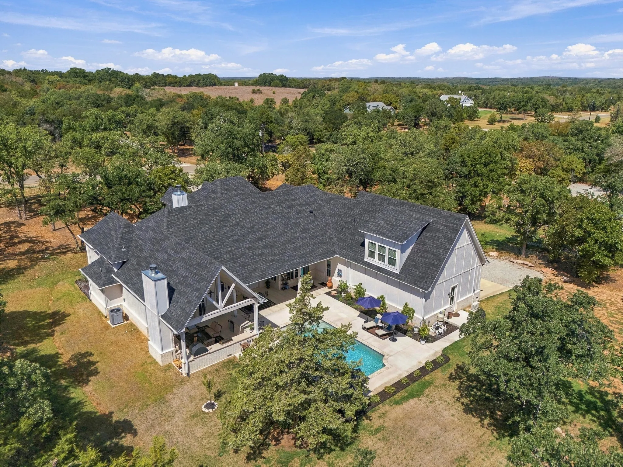 Expansive property featuring a dark grey shingle roof, light-colored siding, and multiple gables