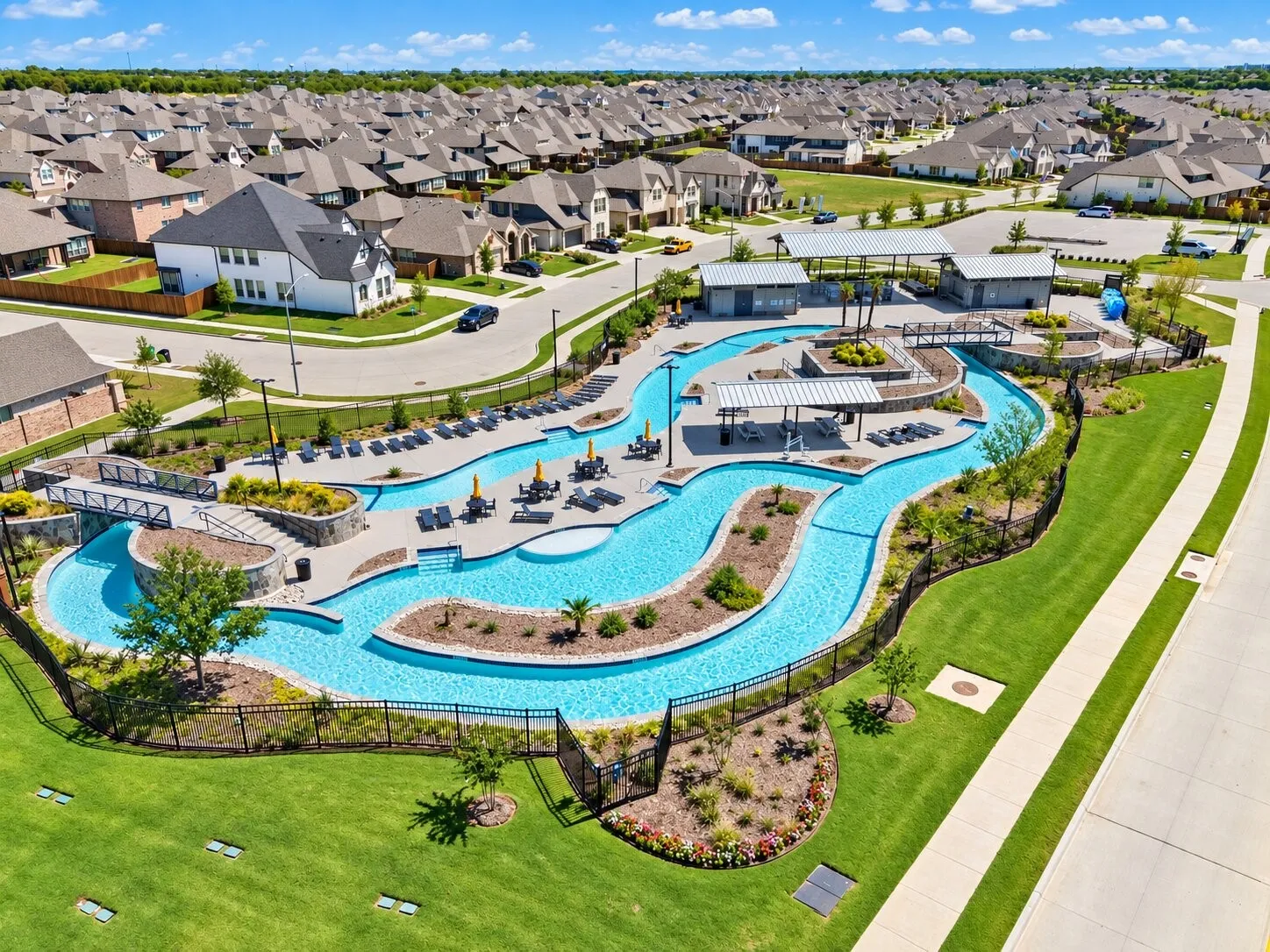 Expansive community pool with a winding lazy river, multiple covered lounge areas, and surrounding landscaped grounds