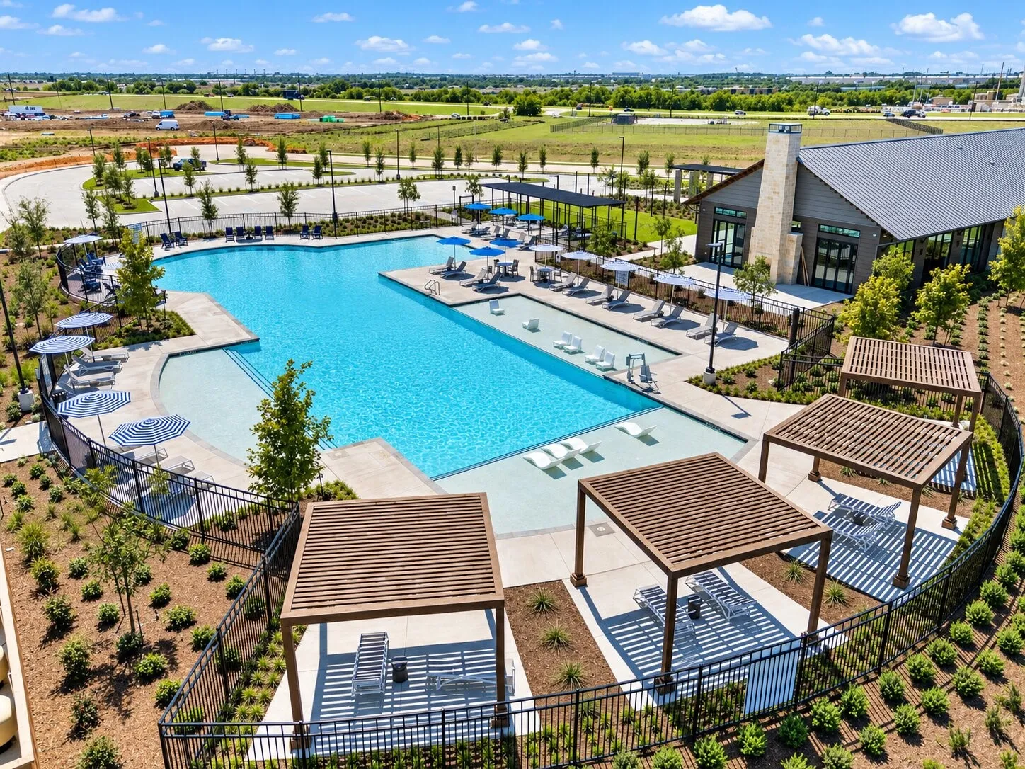 Expansive outdoor pool with multiple lounging areas, shaded pergolas, and a dedicated wading area