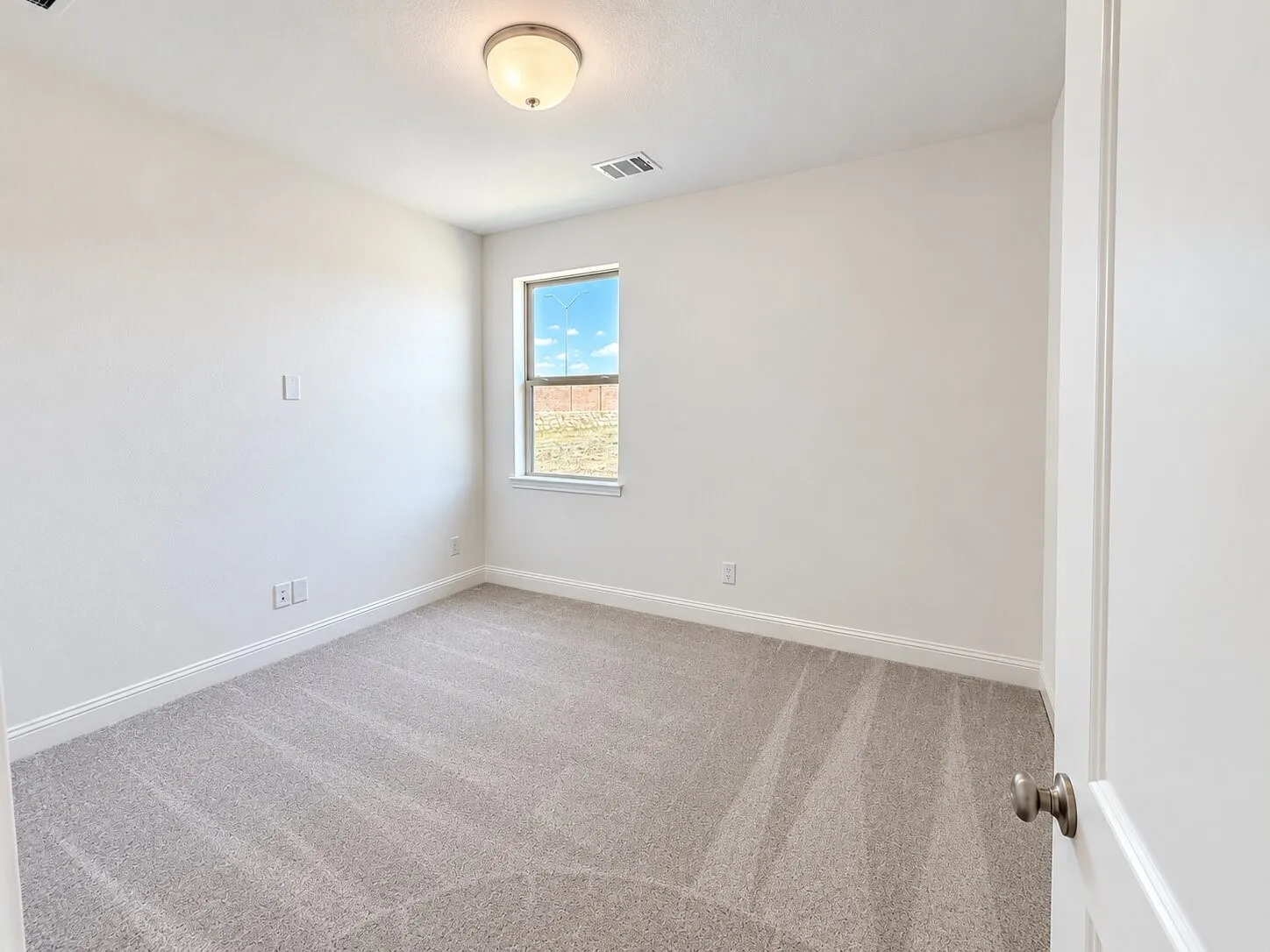 Neutral wall finishes, light-colored carpeting, and a flush mount ceiling light fixture
