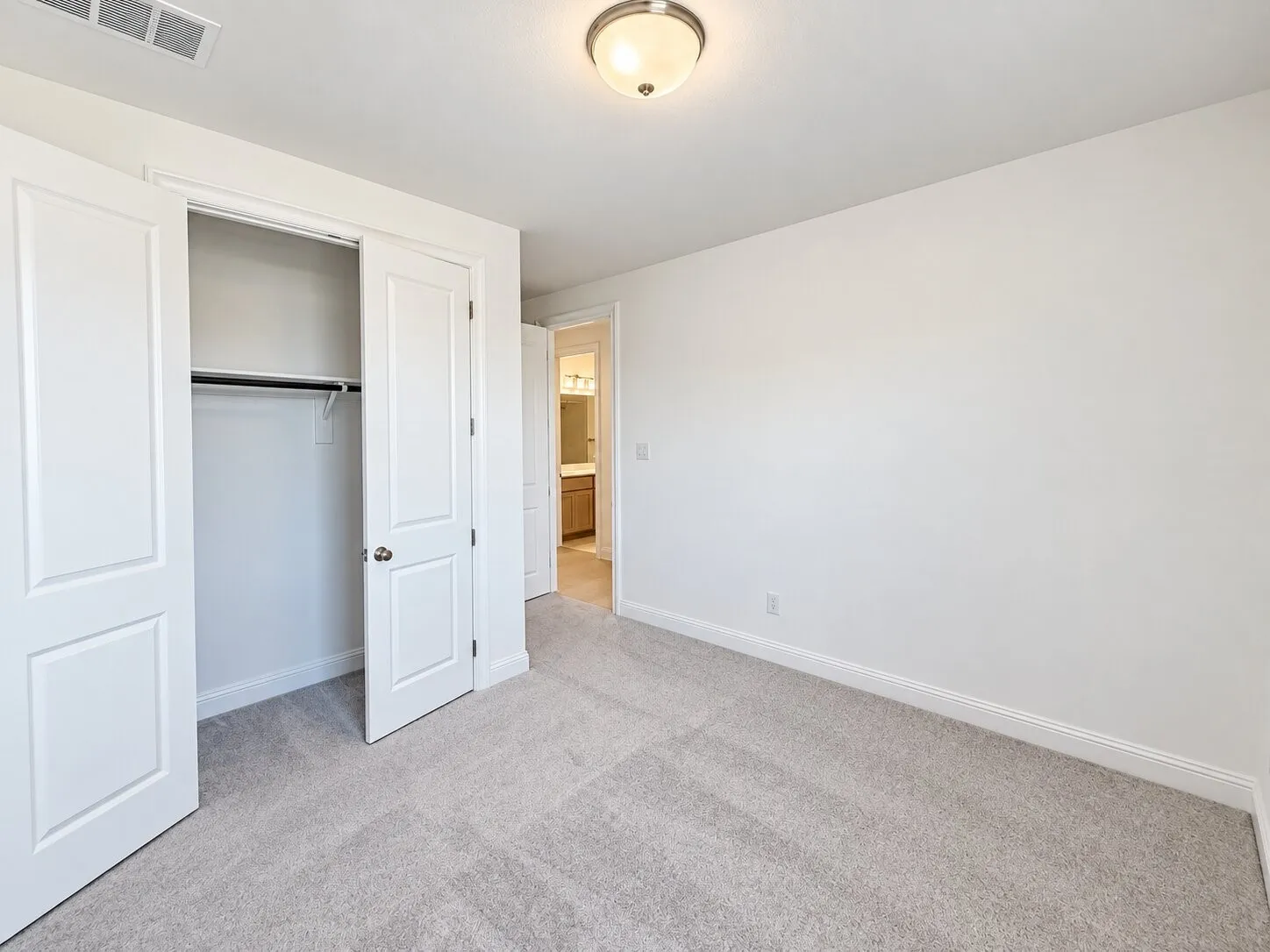 Light-colored carpeting, white walls, and a semi-flush mount ceiling light fixture