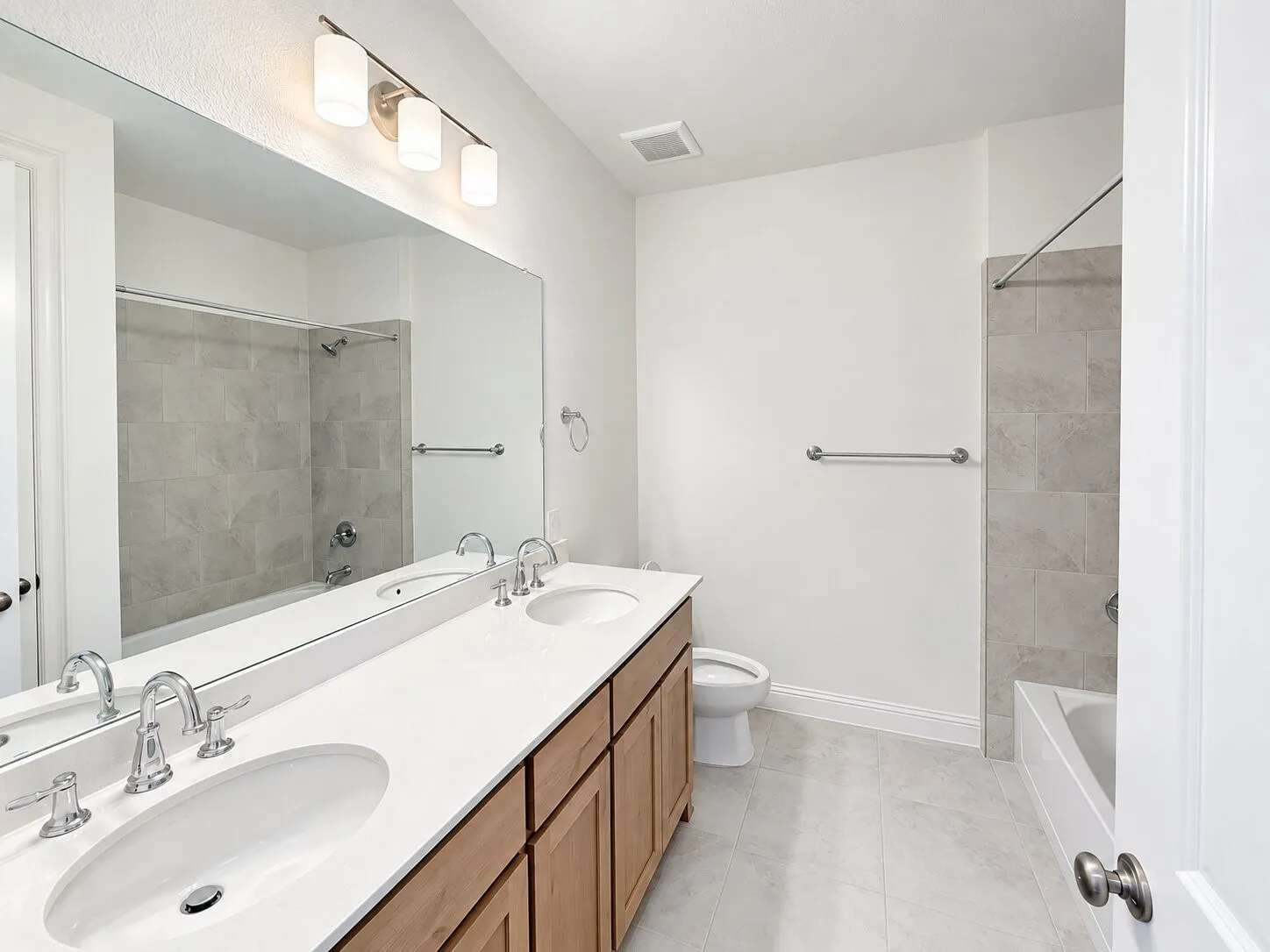 Dual vanity with white undermount sinks, chrome fixtures, and wood-finish cabinetry