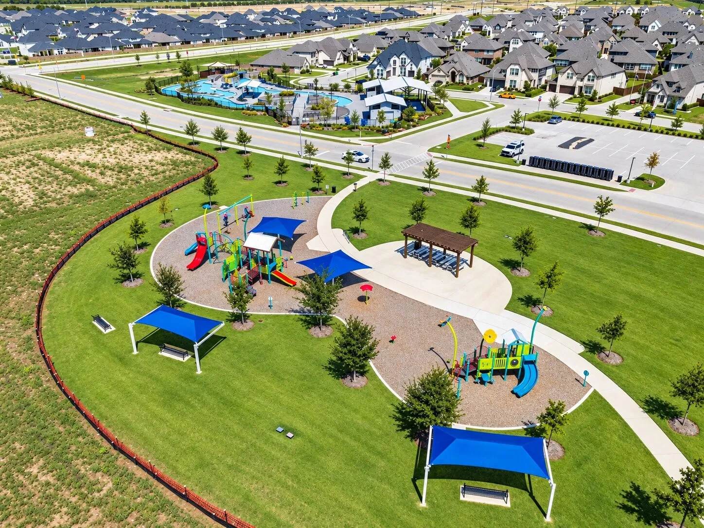 Community playground with multiple play structures, covered seating areas, and surrounding green spaces