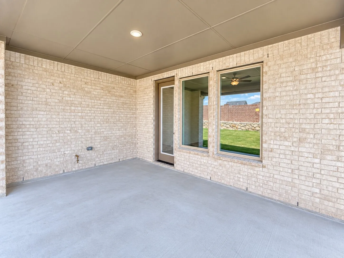 Covered patio featuring a concrete slab, recessed lighting, and a neutral-toned brick exterior