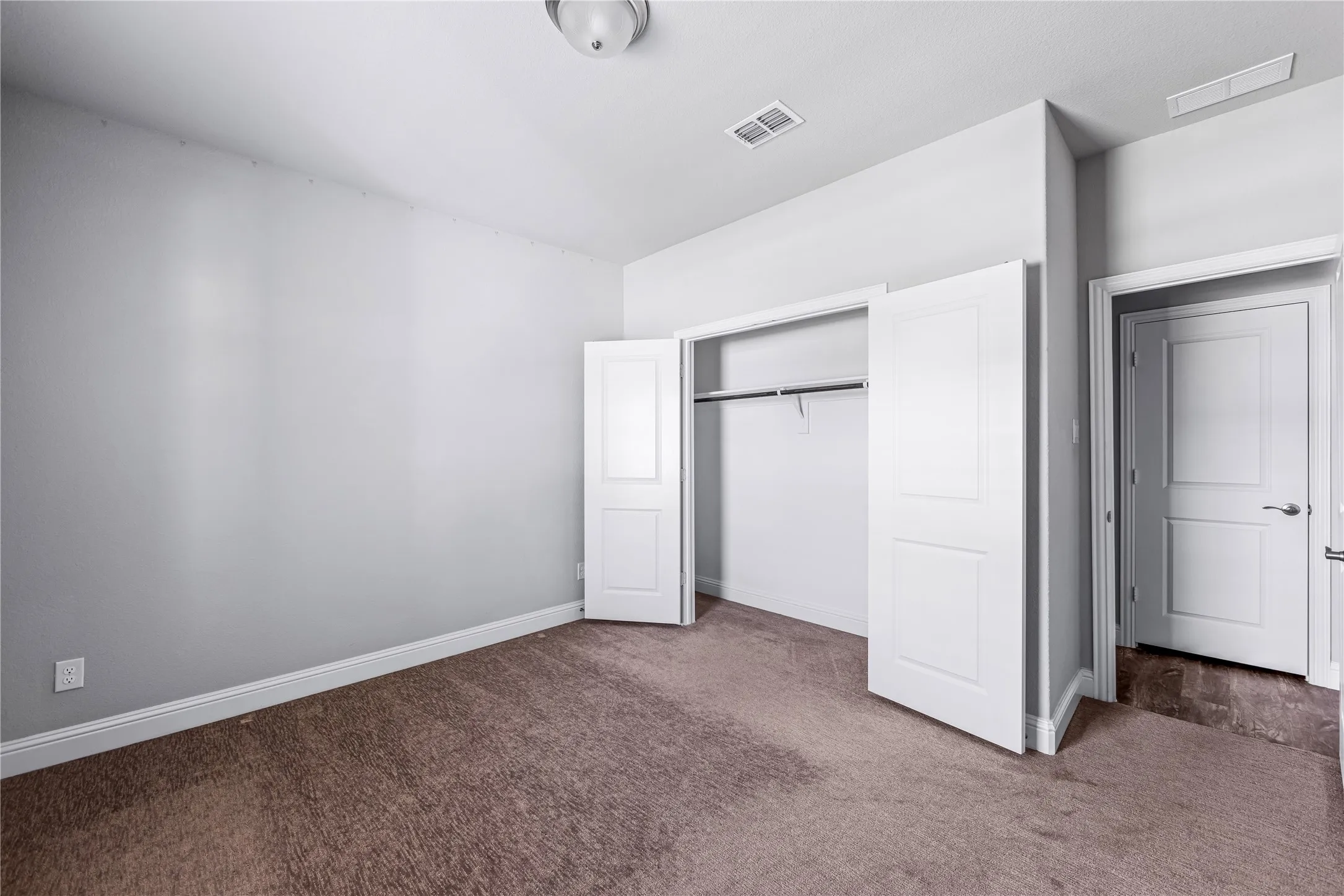 Neutral wall paint, carpet flooring, recessed closet with bi-fold doors, interior panel door