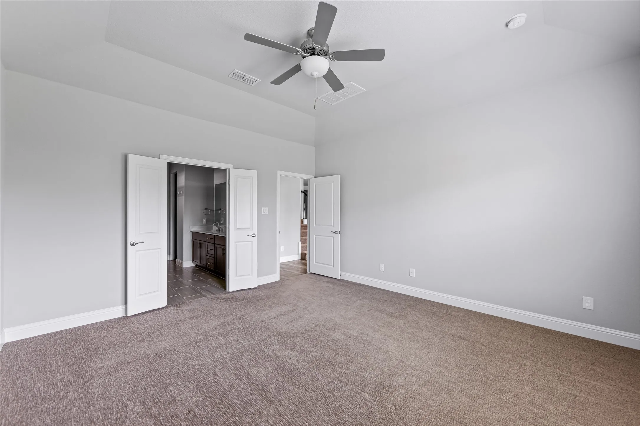 Vaulted ceiling, ceiling fan, neutral wall colors, carpeted flooring, and white interior doors