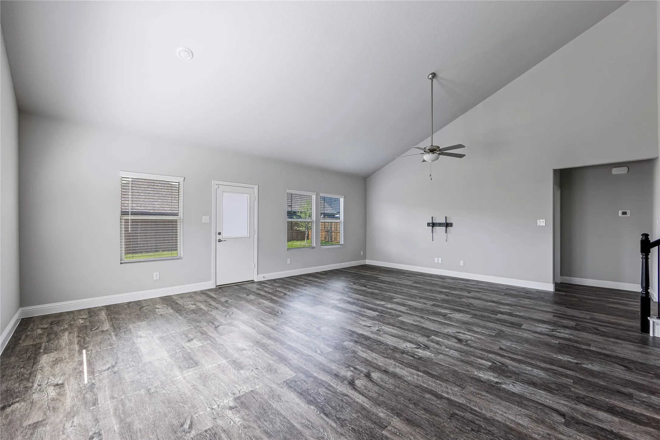 Spacious living area featuring wood-finish flooring, vaulted ceiling, and multiple windows