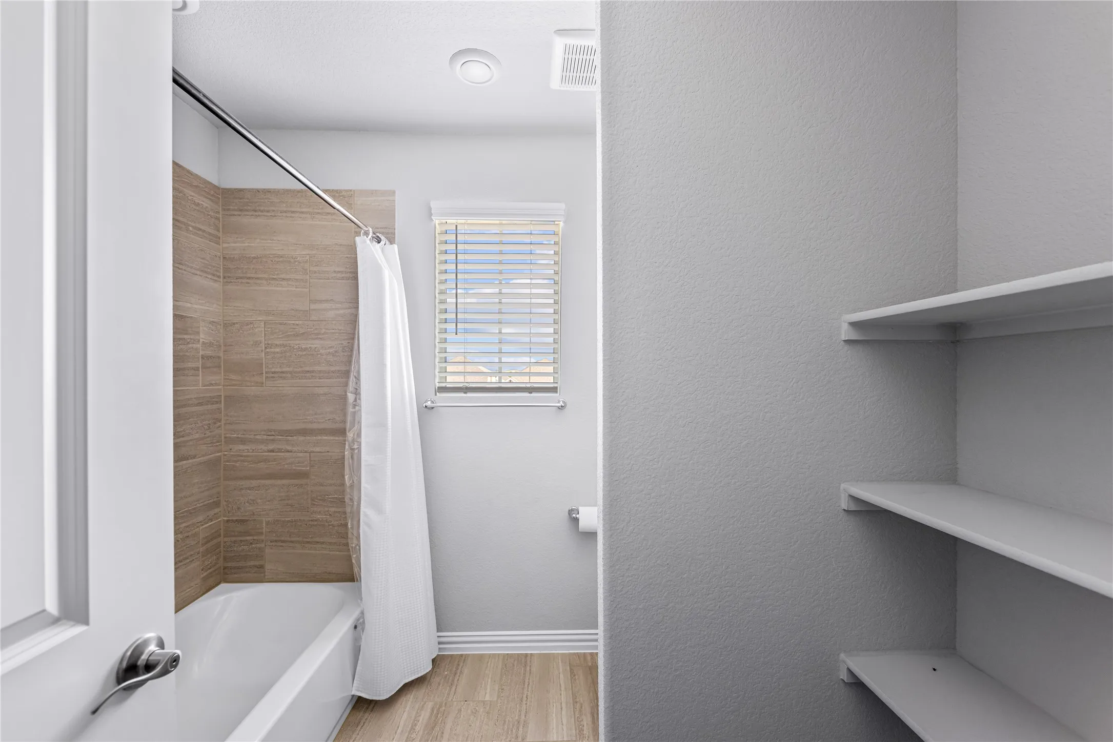 Built-in bathtub with subway tile surround, wood-finish flooring, and built-in shelving
