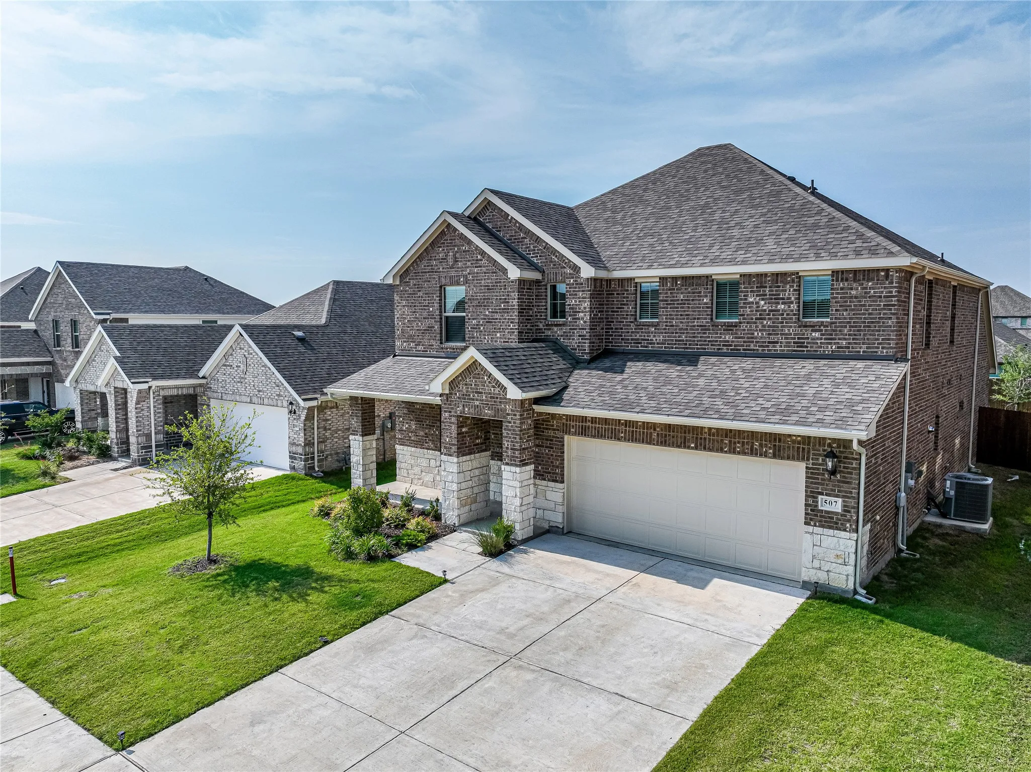 Brick and stone exterior with a two-car garage, concrete driveway, and a covered entry