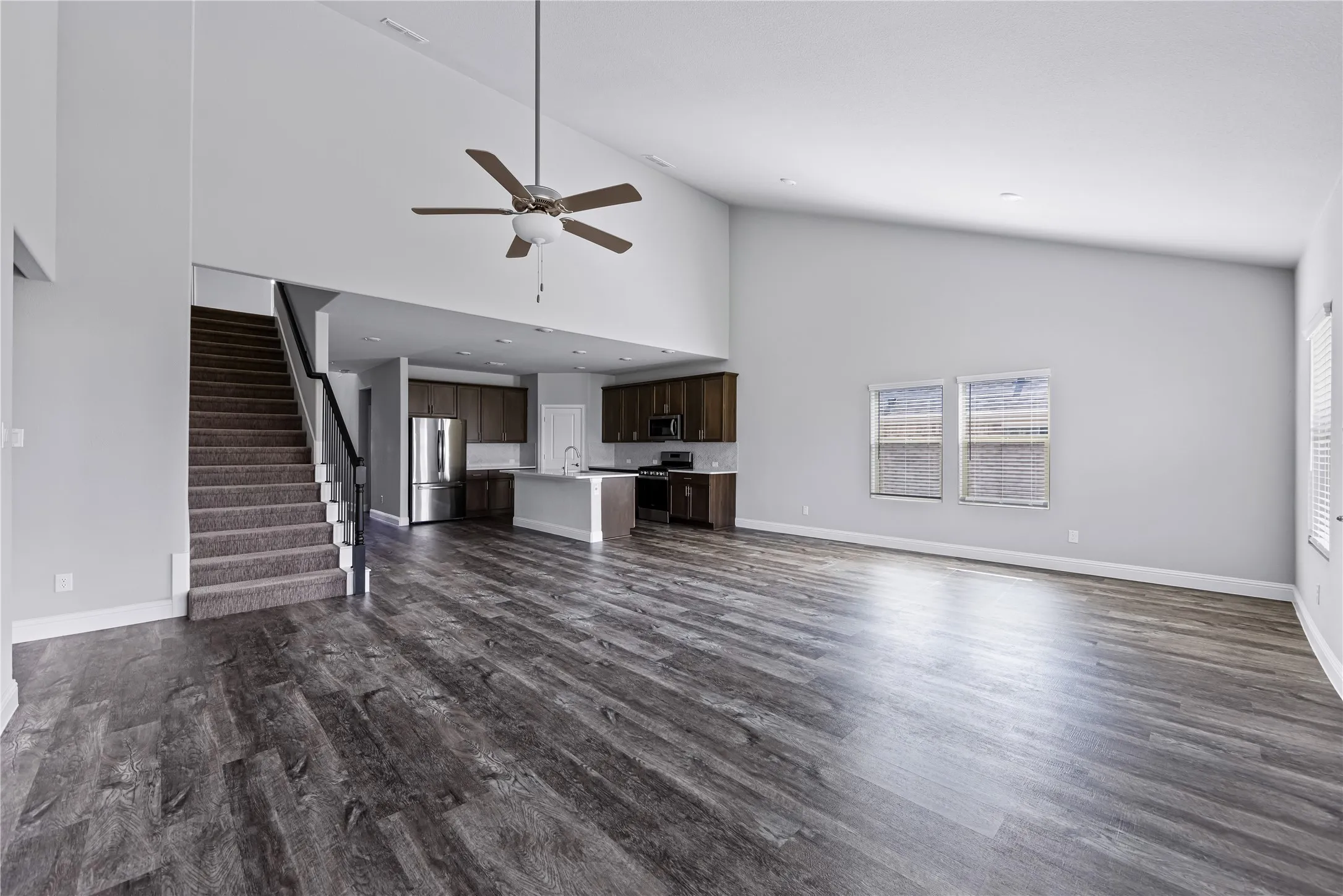 Spacious living area featuring high vaulted ceilings, wood-finish flooring, and a ceiling fan