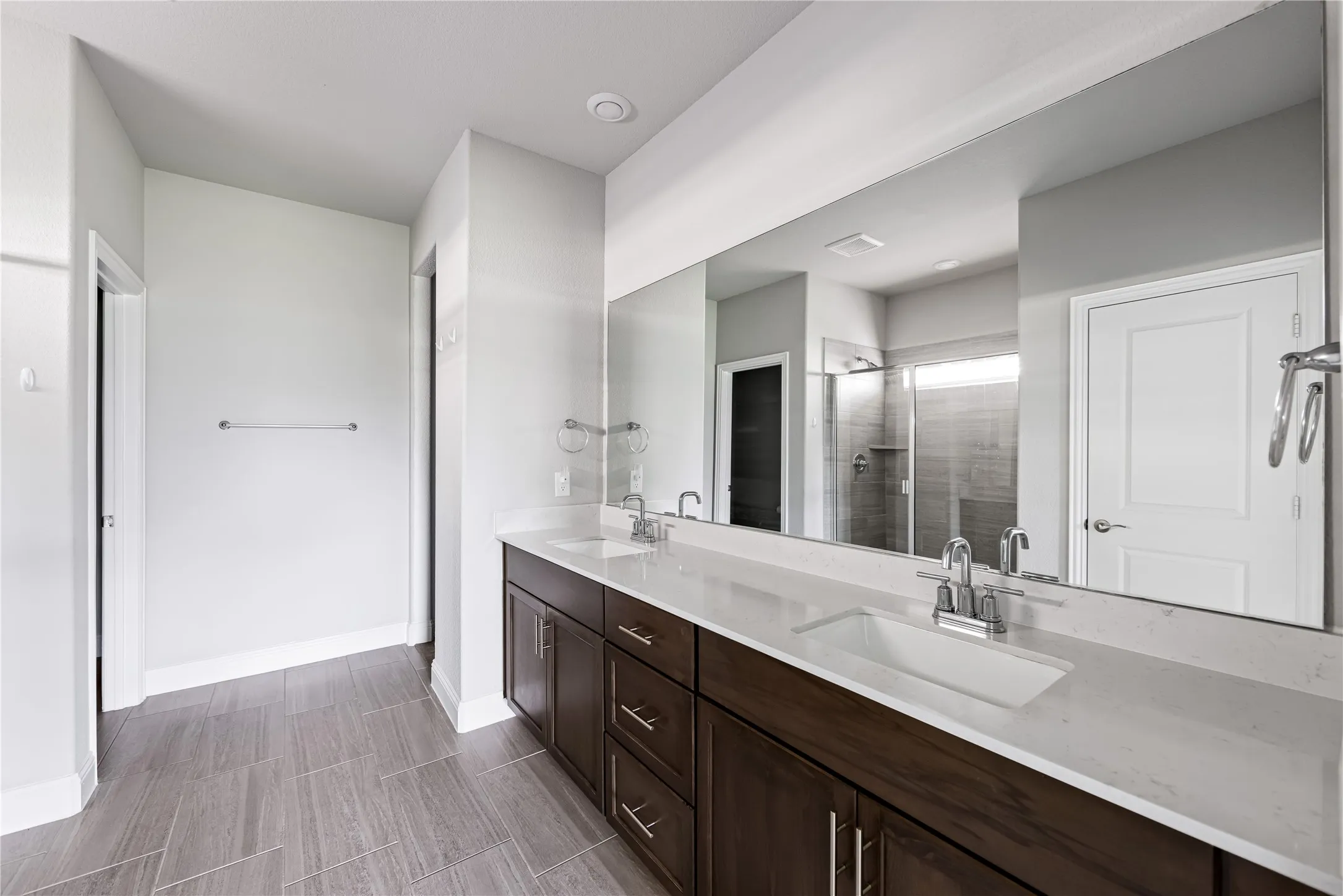 Dual vanity with integrated sinks, white countertops, and dark wood-finish cabinetry