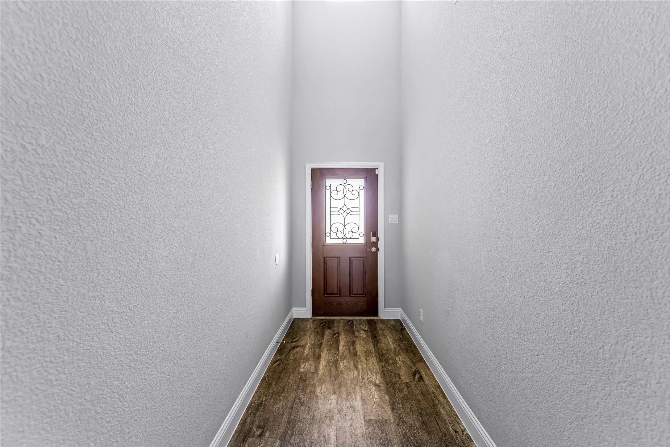 Entryway featuring a wood-finish door with decorative glass, wood-finish flooring, and light-toned textured walls